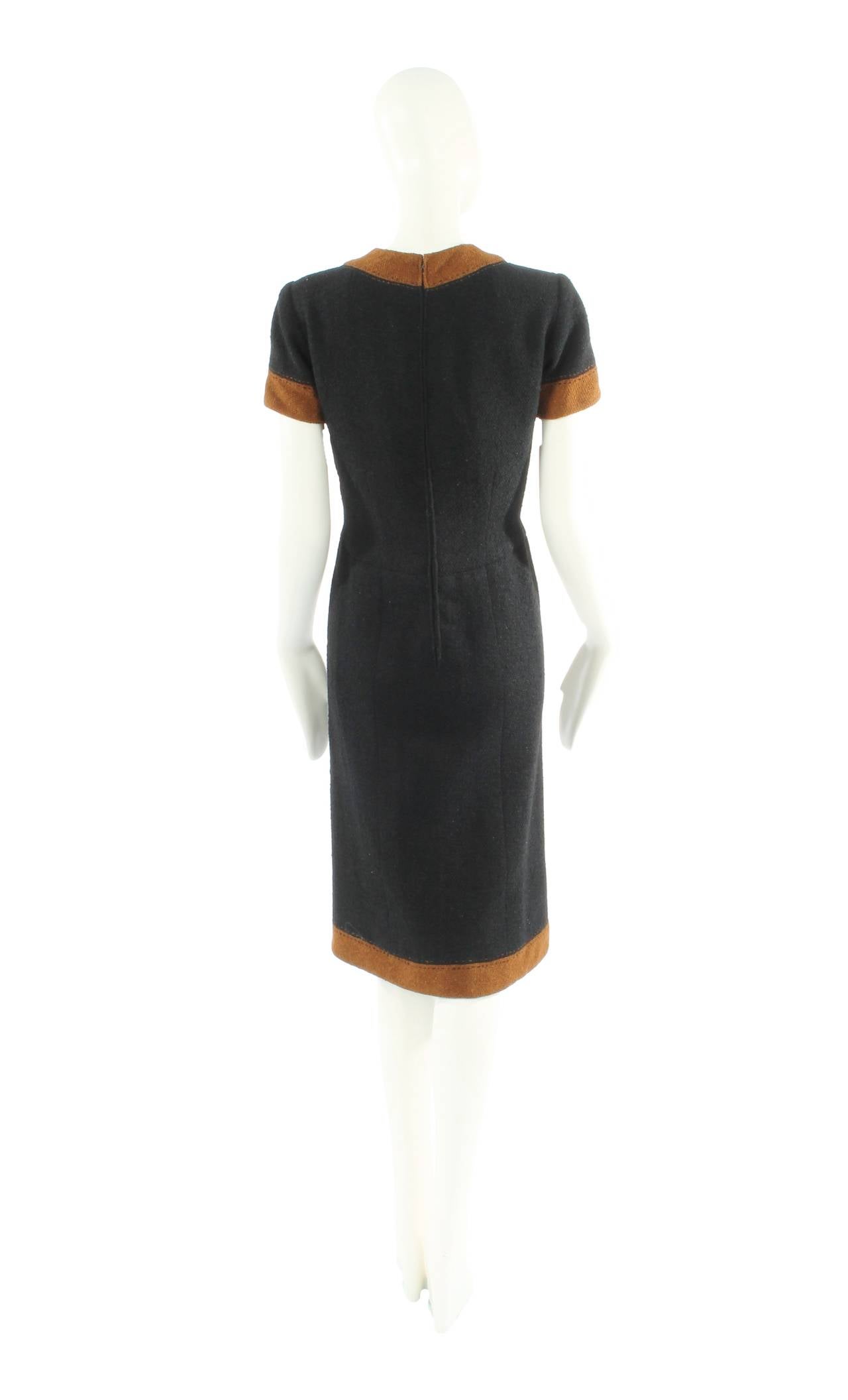 A wonderful haute couture dress by Pierre Balmain, the dress is an eminently wearable item of clothing by one of the greatest couturiers of the 20th century. Crafted in a solid black wool boucle, the dress is edged in tobacco-coloured wool boucle