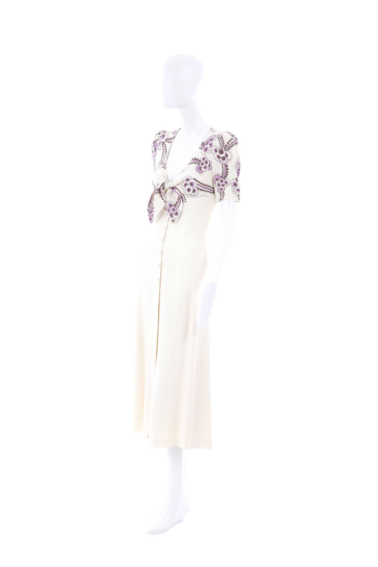 An iconic and covetable dress by Ossie Clark featuring Celia Birtwell’s instantly recognizable Mystic Daisy print, the dress details a keyhole bust with printed tie front and an ivory block colour skirt with matching moss crepe buttons.

Ossie