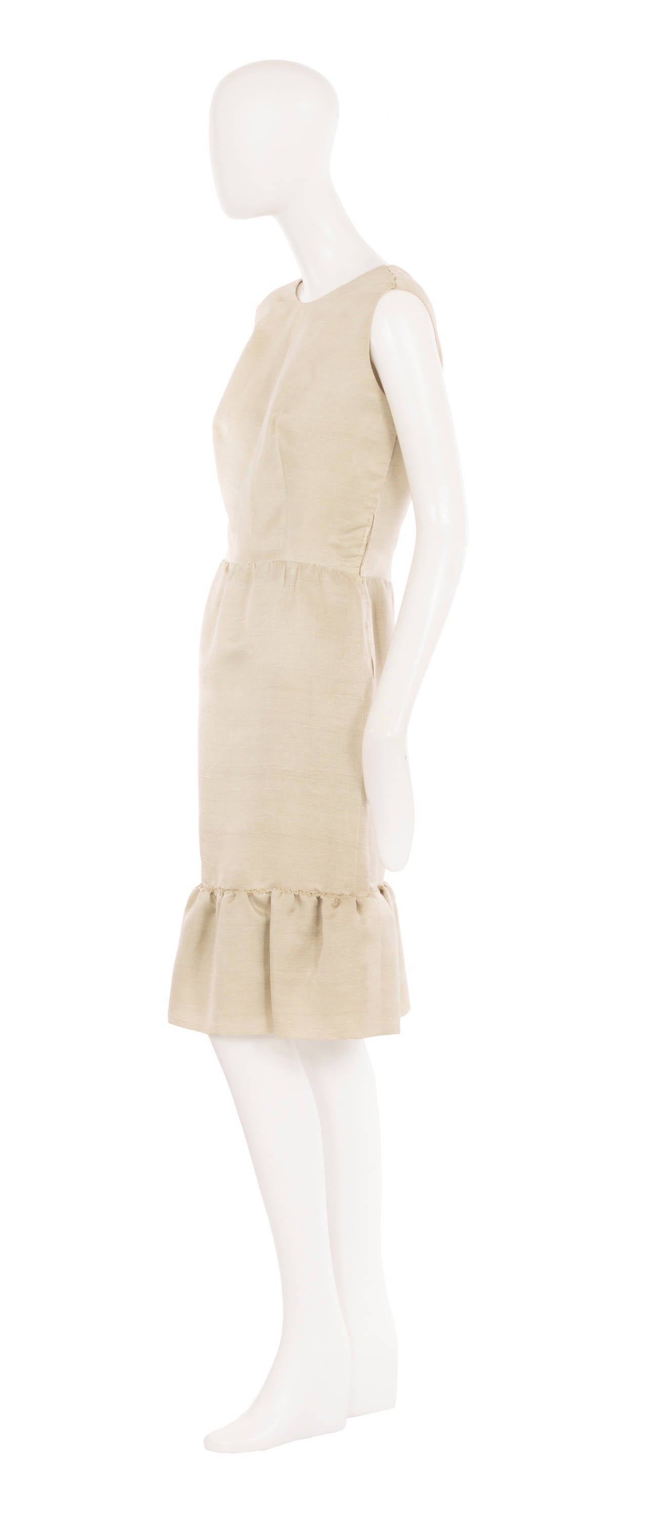 This beautifully constructed haute couture cocktail dress was designed by Balenciaga for his Spanish label Eisa. Made of a pearlescent oyster-coloured silk that has a subtle shimmer, the dress features a round neckline, scooping lower to the back,