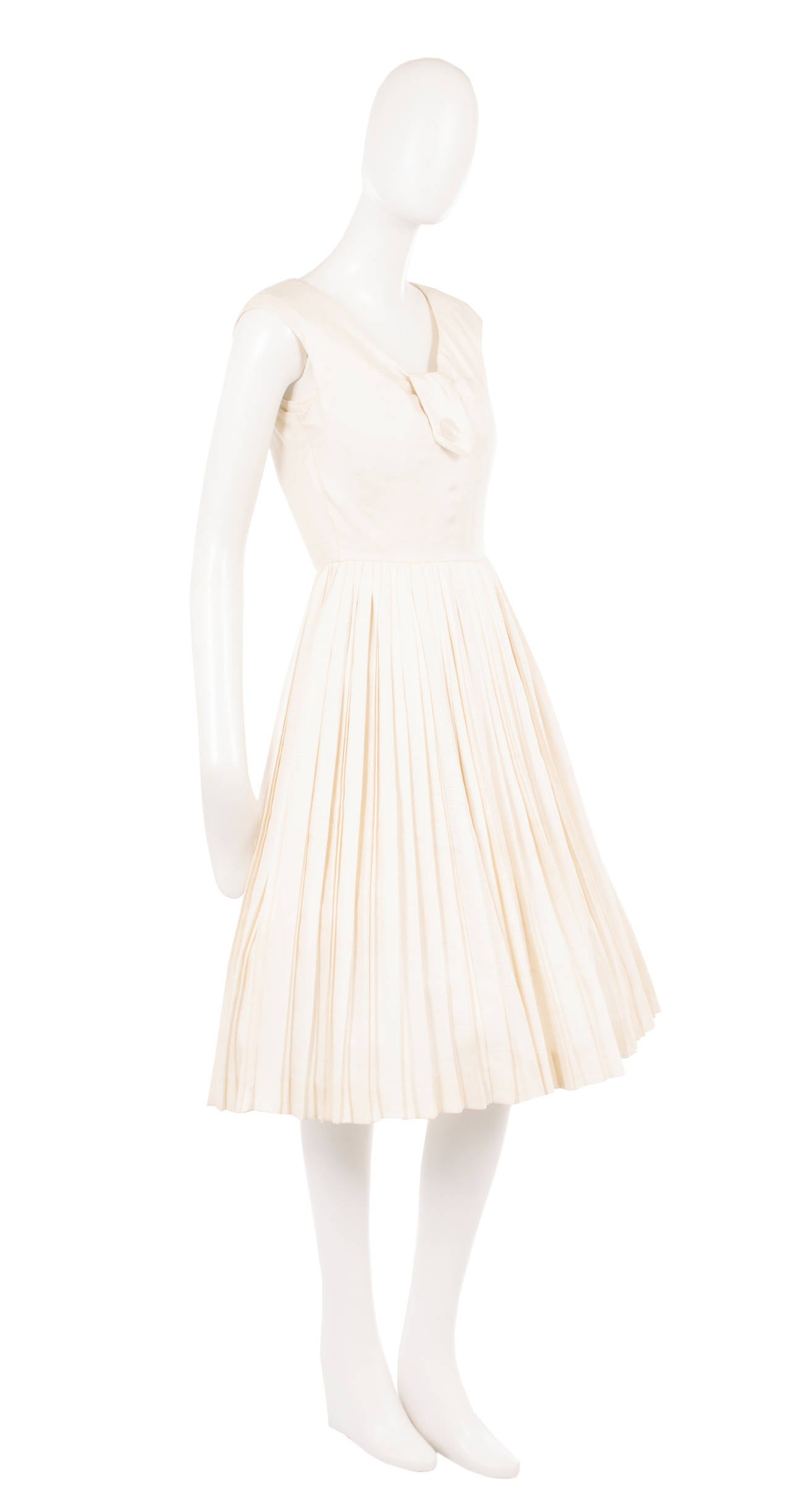 The perfect summer alternative to an LBD, this Dior dress is constructed from ivory silk and features cap sleeves and a button detail to the neckline. Retaining the famous Dior silhouette, with a nipped in waist, the dress has a lighter feel with a