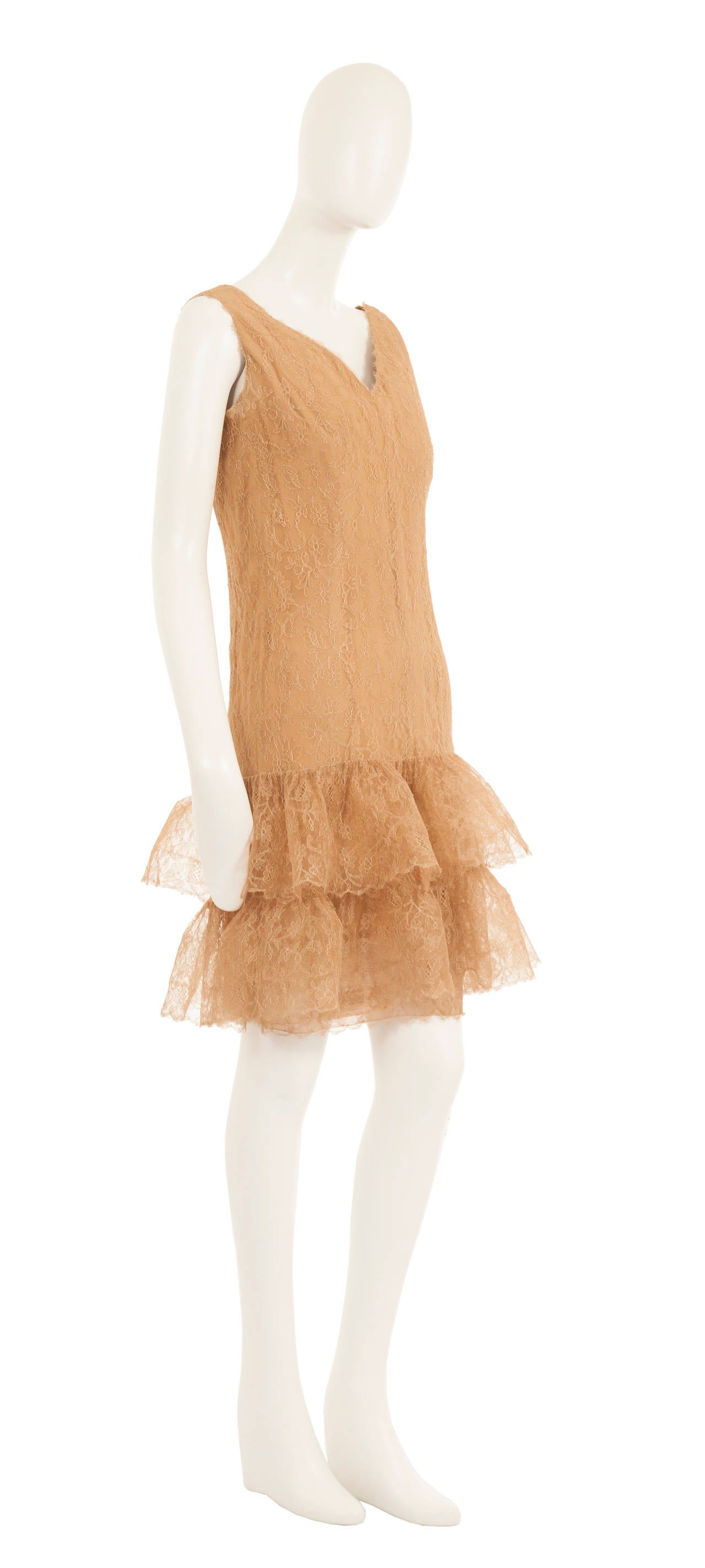 A stunning piece of haute couture, this Balenciaga cocktail dress is constructed in caramel lace and lined in silk. The perfect choice for parties and cocktail events, the sleeveless dress features a flattering v-neckline and drop waist silhouette.