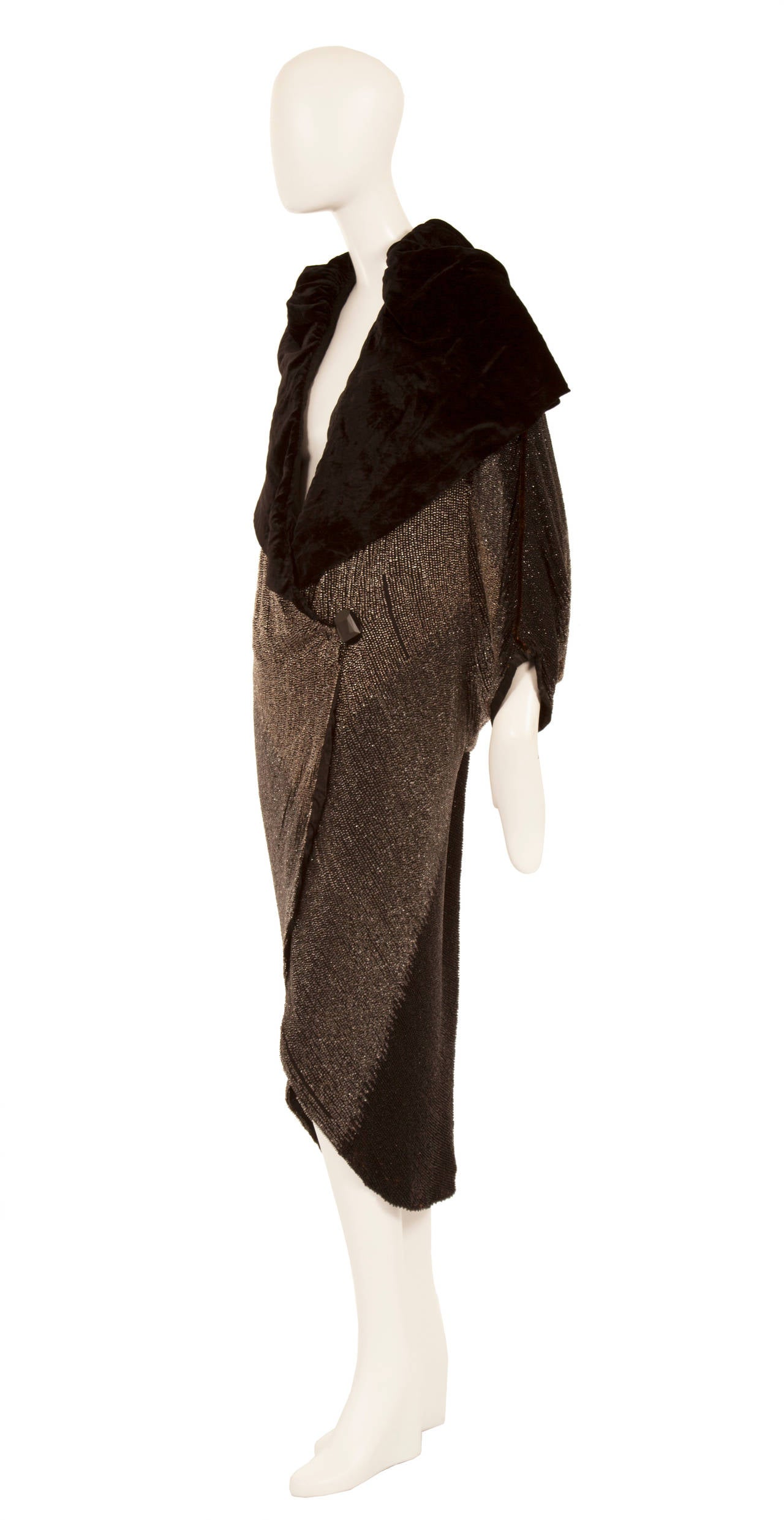 This exquisite coat is an exceptional piece of early 20th century haute couture by Paul Poiret. Hand beaded with thousands of tiny bugle beads, the coat has an ombre effect, fading from black through to light grey, and features an oversized shawl