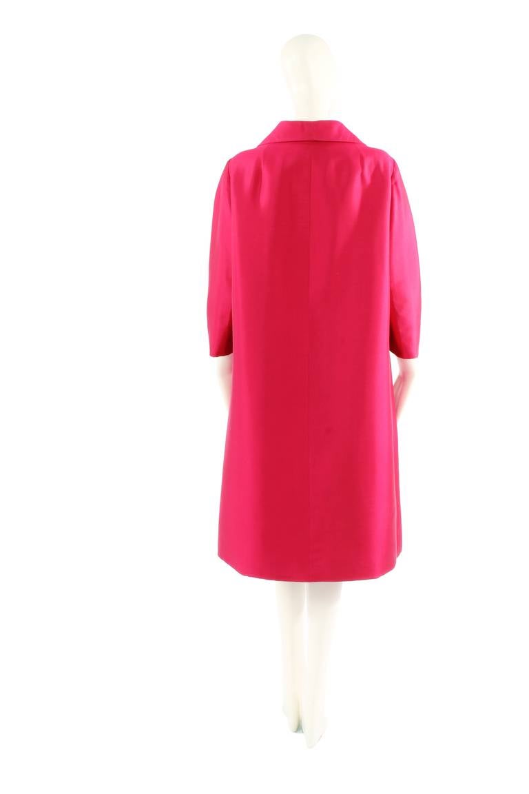 This magnificent haute couture coat from the Dior Spring Summer 1963 collection is beautifully cut and shaped in the front to hide two large pockets, giving it an extremely contemporary feel. Crafted in the finest raspberry silk and lined in
