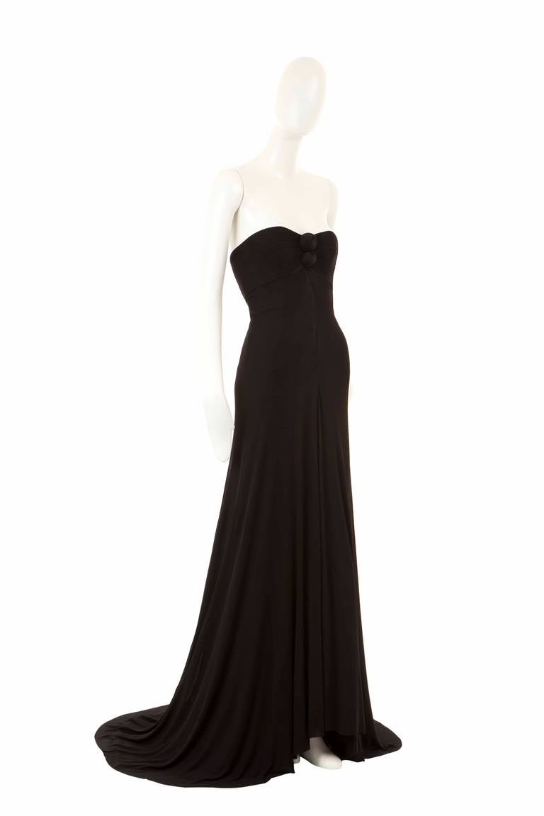 This iconic, strapless dress is a dramatic piece of sinuous haute couture from Madame Grès. Featuring a boned, lined bodice and detailing ruched knots at the bust, the dress is stealthily chic as it flows from the original fasteners and poppers and