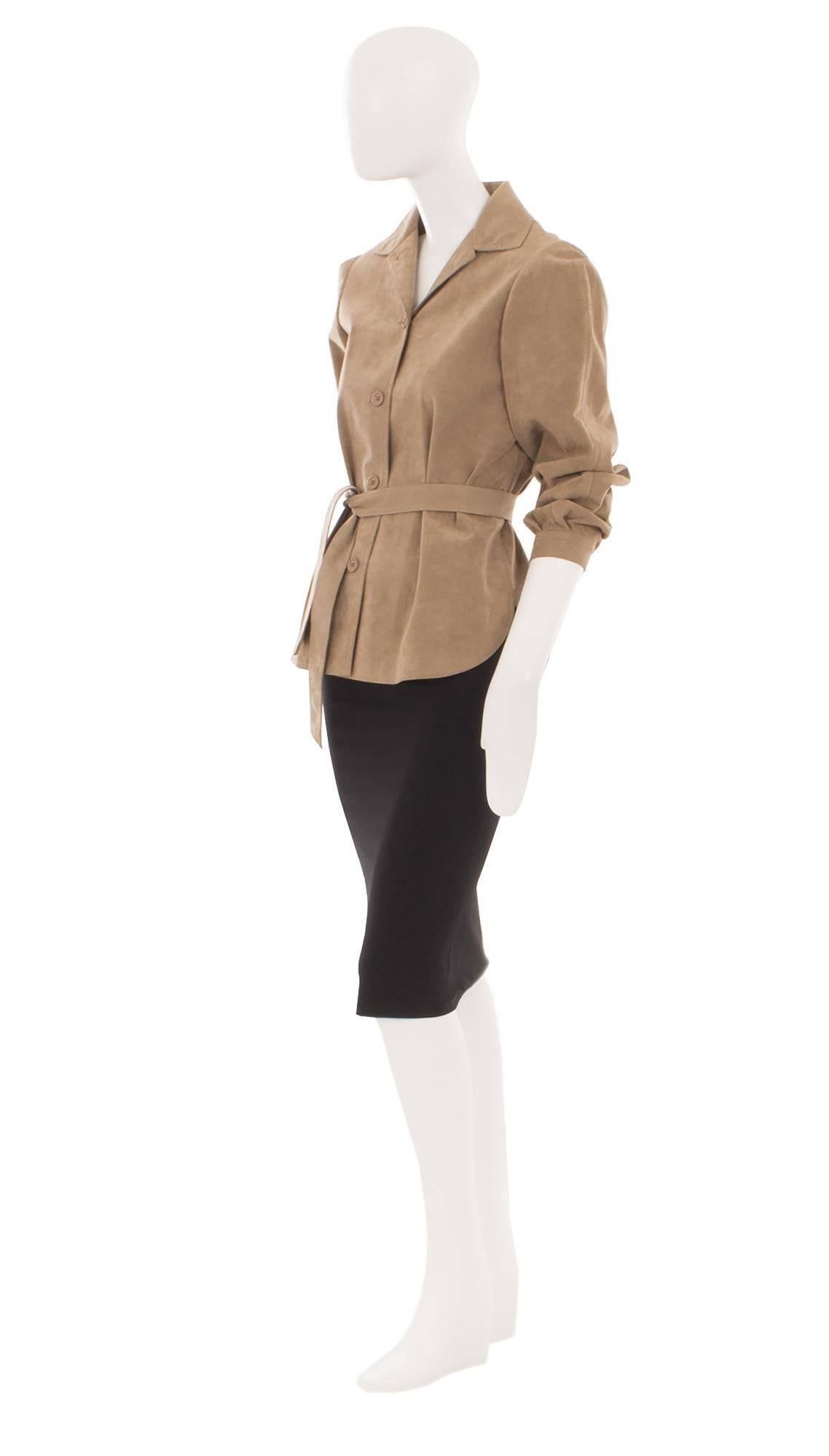 Constructed in tan Ultrasuede, this beautifully cut Halston jacket will be sure to hit the right note in the Boardroom. The longer length, tied at the waist with the original fabric matched belt, elongates the body while the wide sleeves add volume