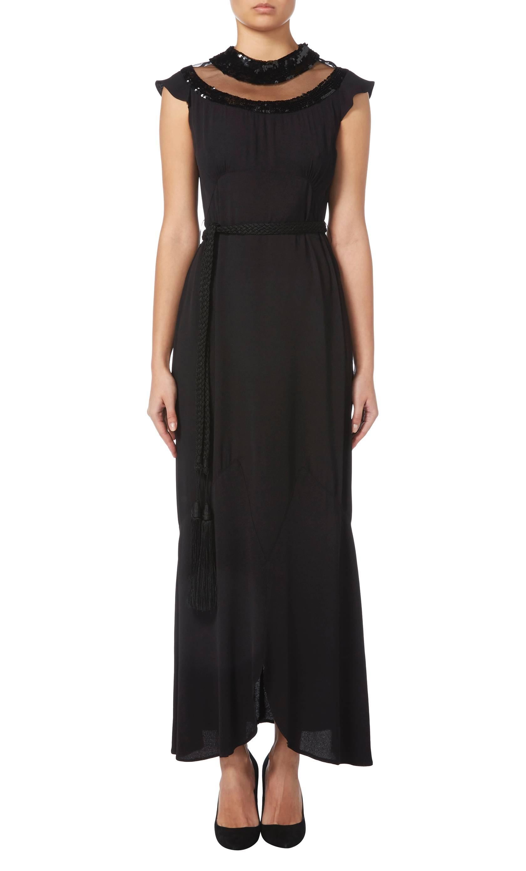 A stunning piece of Jean Patou from the early 1930s, this maxi dress is constructed in black crepe and features a cutaway neckline with a black silk tulle panel trimmed with black sequins, which adds subtle sparkle. Featuring capped sleeves and a