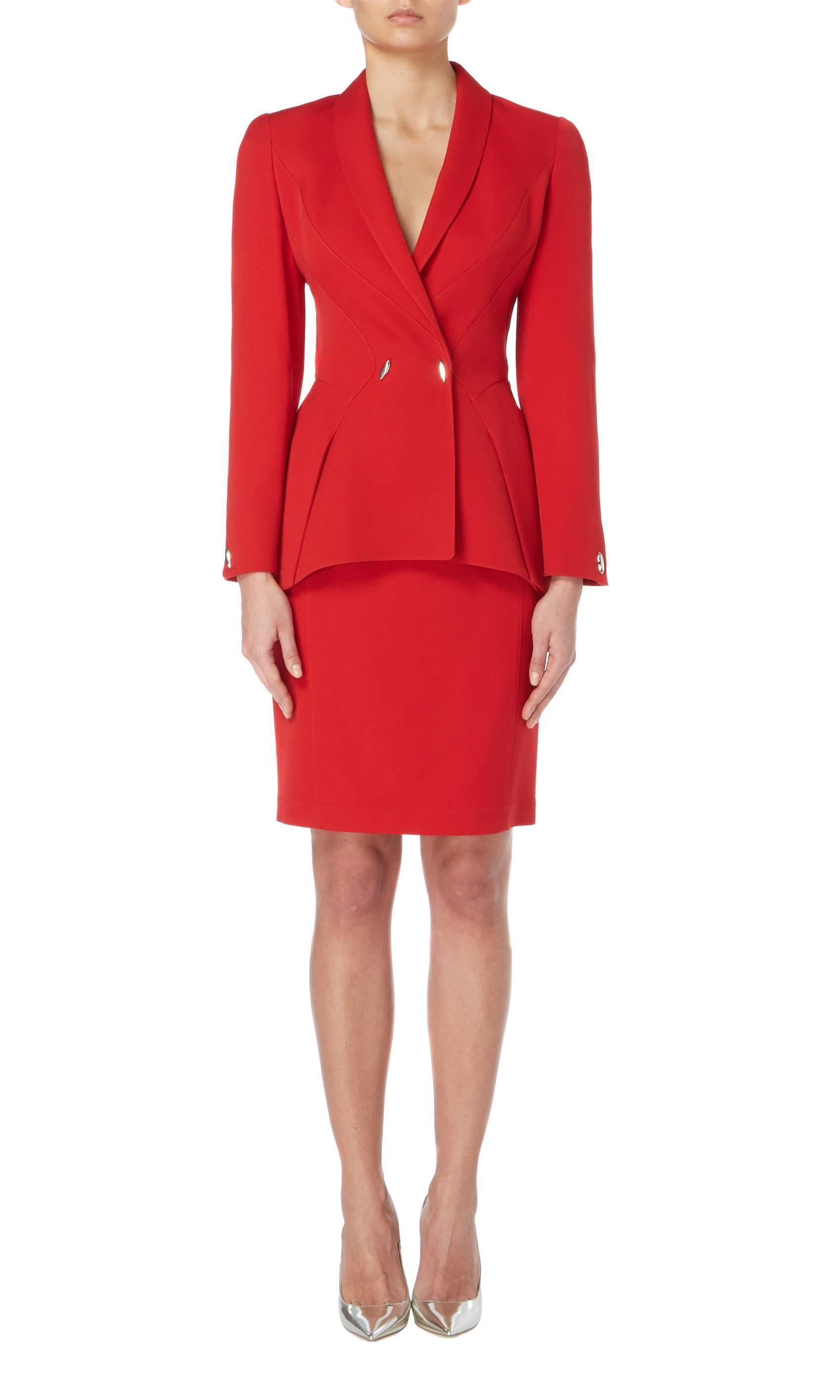A fantastic example of the legendary Thierry Mugler’s signature silhouette, this skirt suit is sharply tailored in red wool and comprises of a long sleeved jacket and skirt. The jacket features a nipped in waist, creating a flattering hourglass
