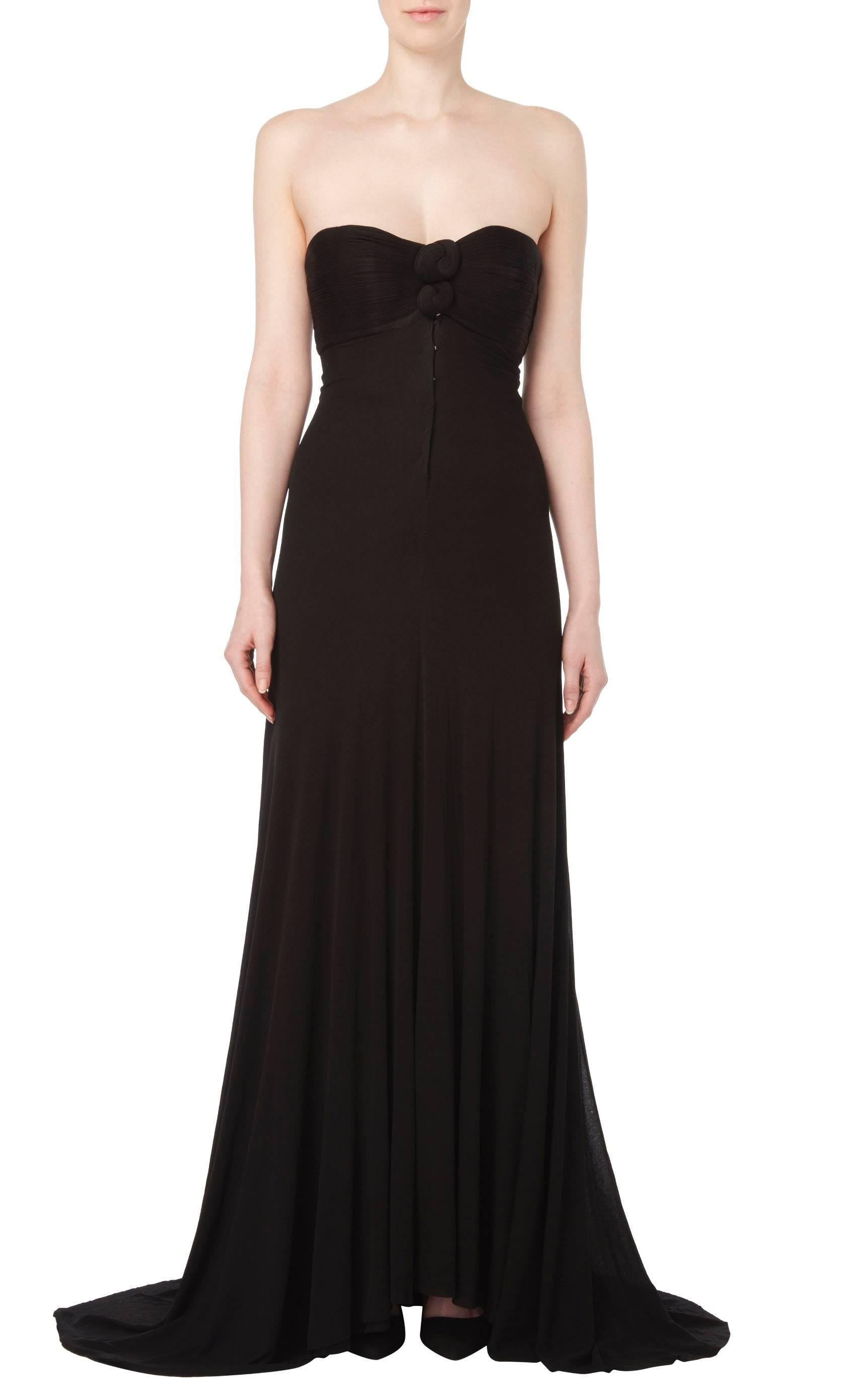 This iconic, strapless dress is a dramatic piece of sinuous haute couture from Madame Grès. Featuring a boned, lined bodice and detailing ruched knots at the bust, the dress is stealthily chic as it flows from the original fasteners and poppers and