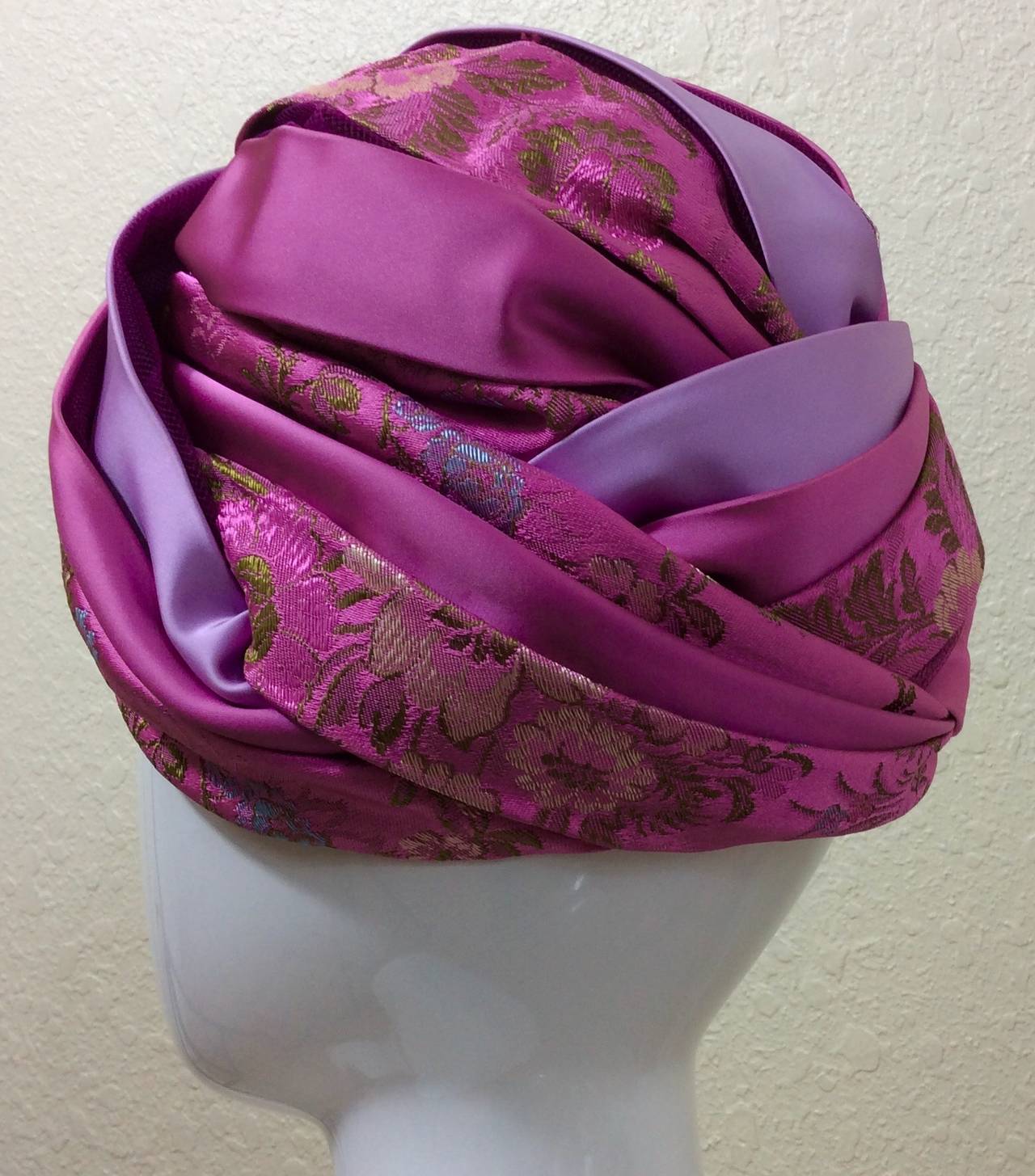 This is a magnificent vintage Christian Dior chapeaux turban. Featuring a mixture of satin in shads of pink and lavender, with alternating bands of a floral brocade with hints of gold and violet. Peaking through the bands of satin and brocade are