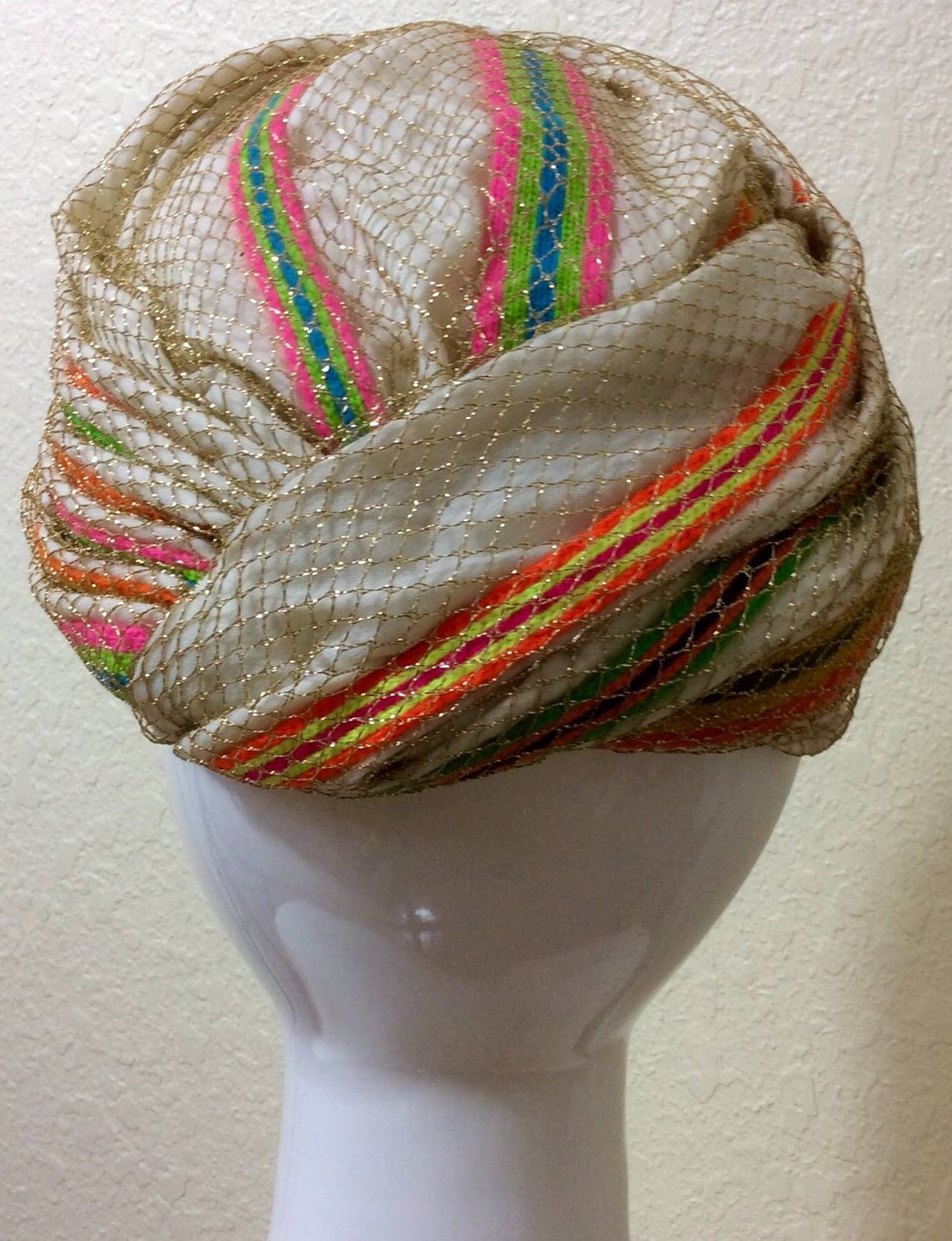This magnificent turban form Christian Dior chapeaux is ivory with rainbow braided and knit stripes throughout, and topped off with a layer of gold netting. The inside is fully lined. Excellent condition
The diameter is about 8