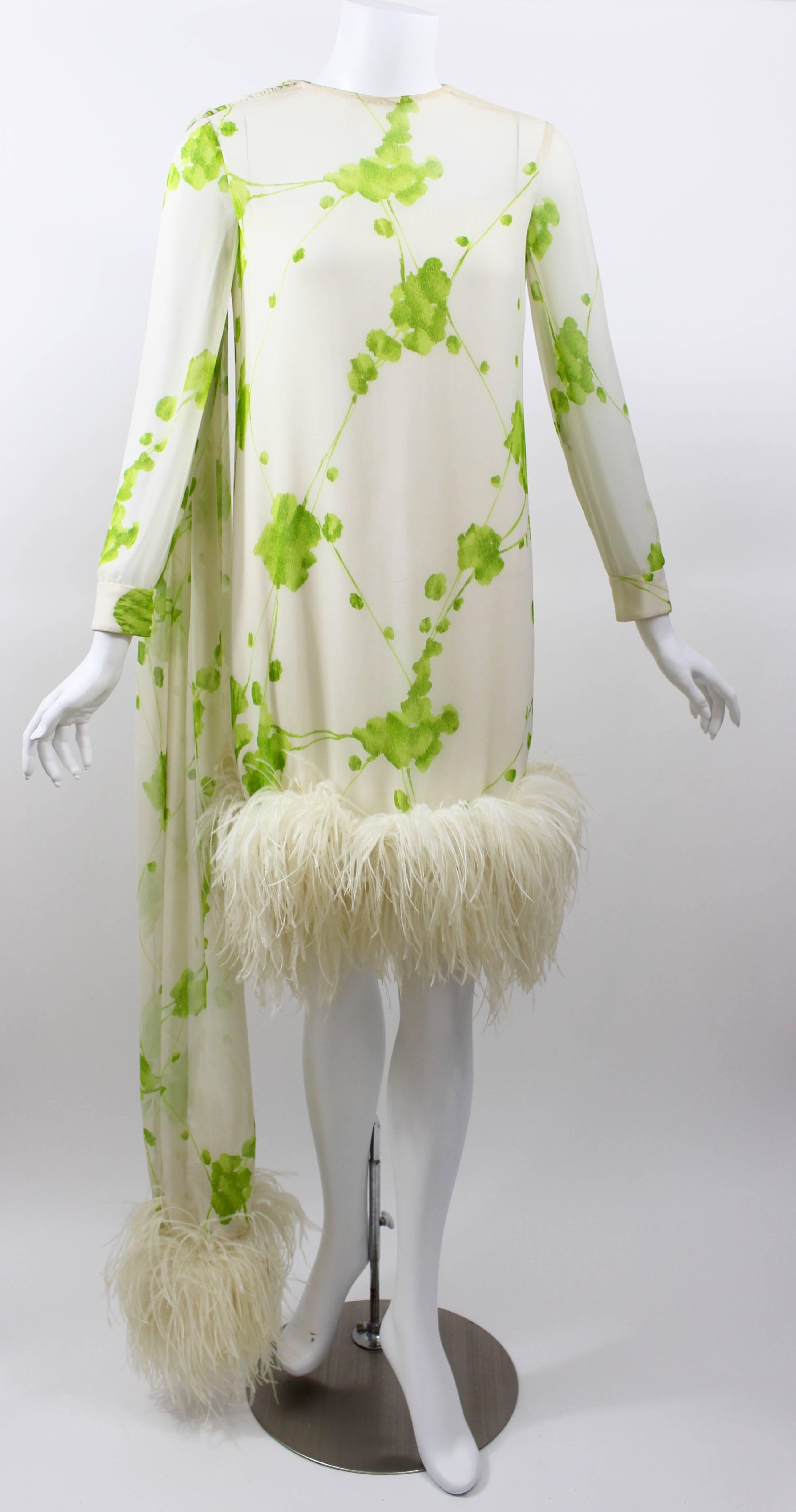 A magnificent 1960s Pierre Cardin cocktail party and evening dress. Fashioned from sheer silk chiffon in ivory with a light green abstract floral print and  trimmed at the hem with ivory ostrich feathers. I love the  long show stopping  feather