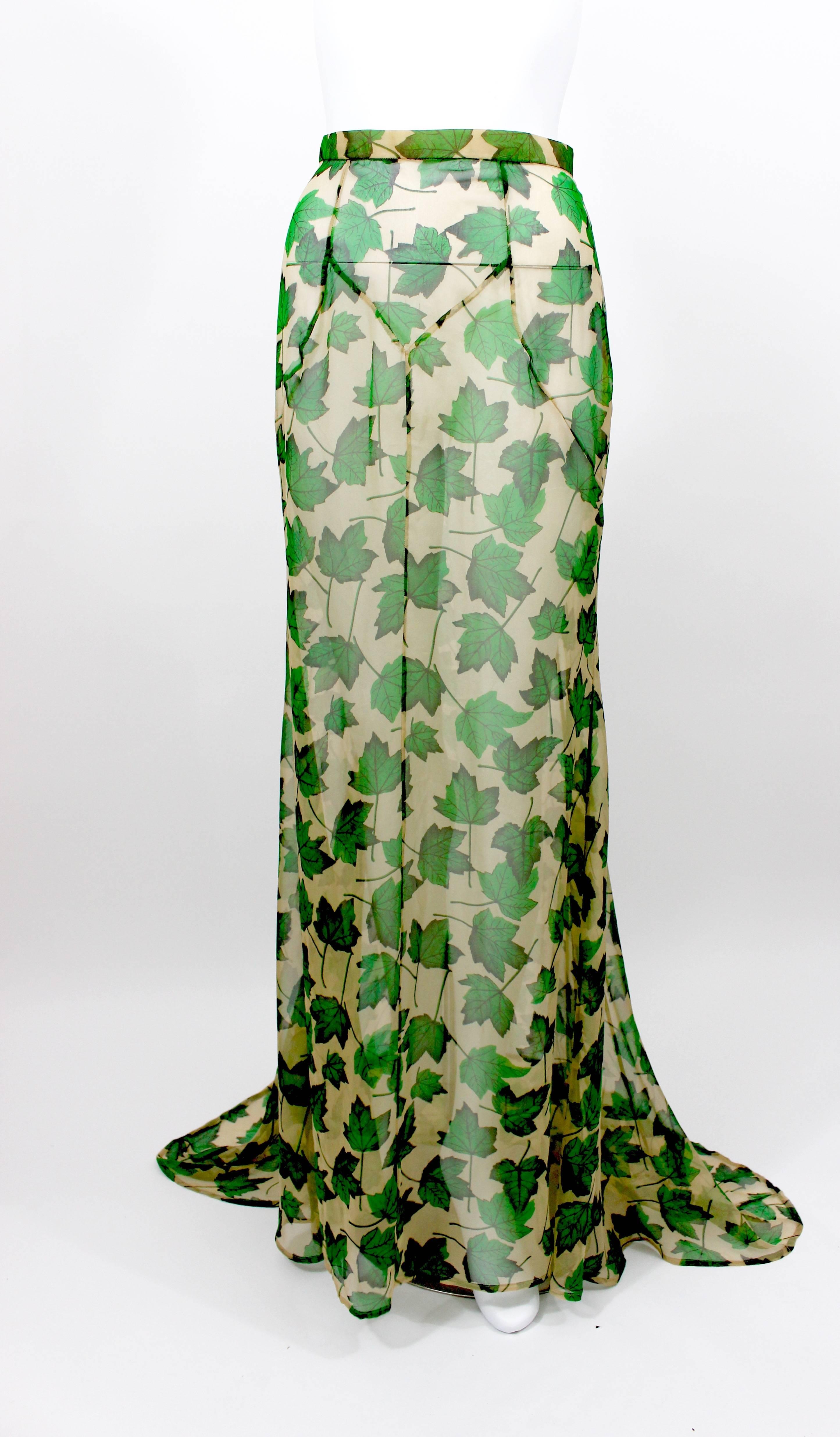 A beautiful figure flattering gown skirt with a train from Dolce & Gabbana. Fashioned from transparent beige silk chiffon with a vivid green and black falling leaves print throughout. 
Measurements: 
Waist: 25 inches
Hips: 36 inches 
Length