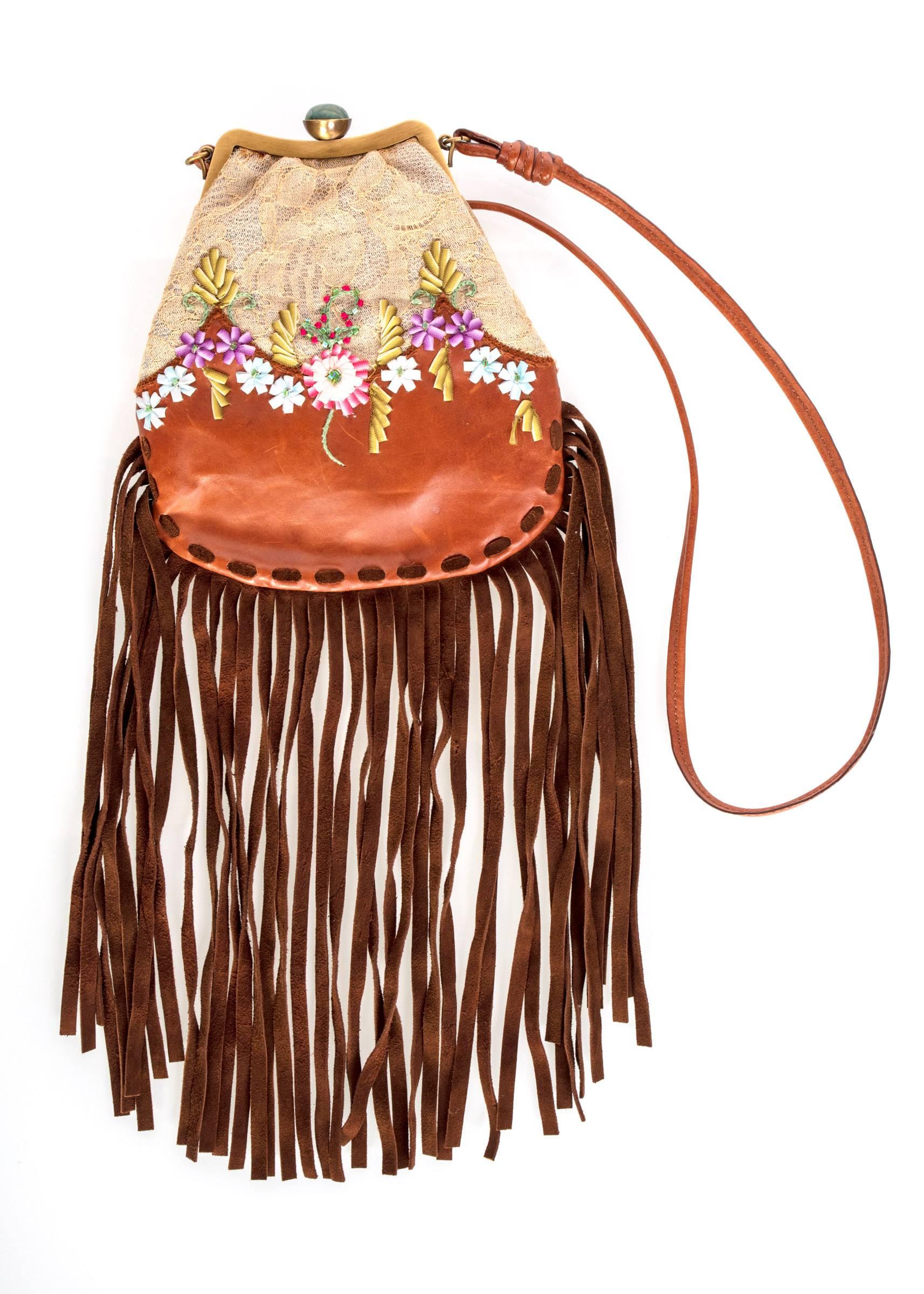 Beige lace and brown leather with embroidered ribbon flowers embellished with beads.
The top of the purse is framed in a brass colored metal with colorful enameled flowers. 
The clasp is set with a polished green stone. The shoulder strap is leather