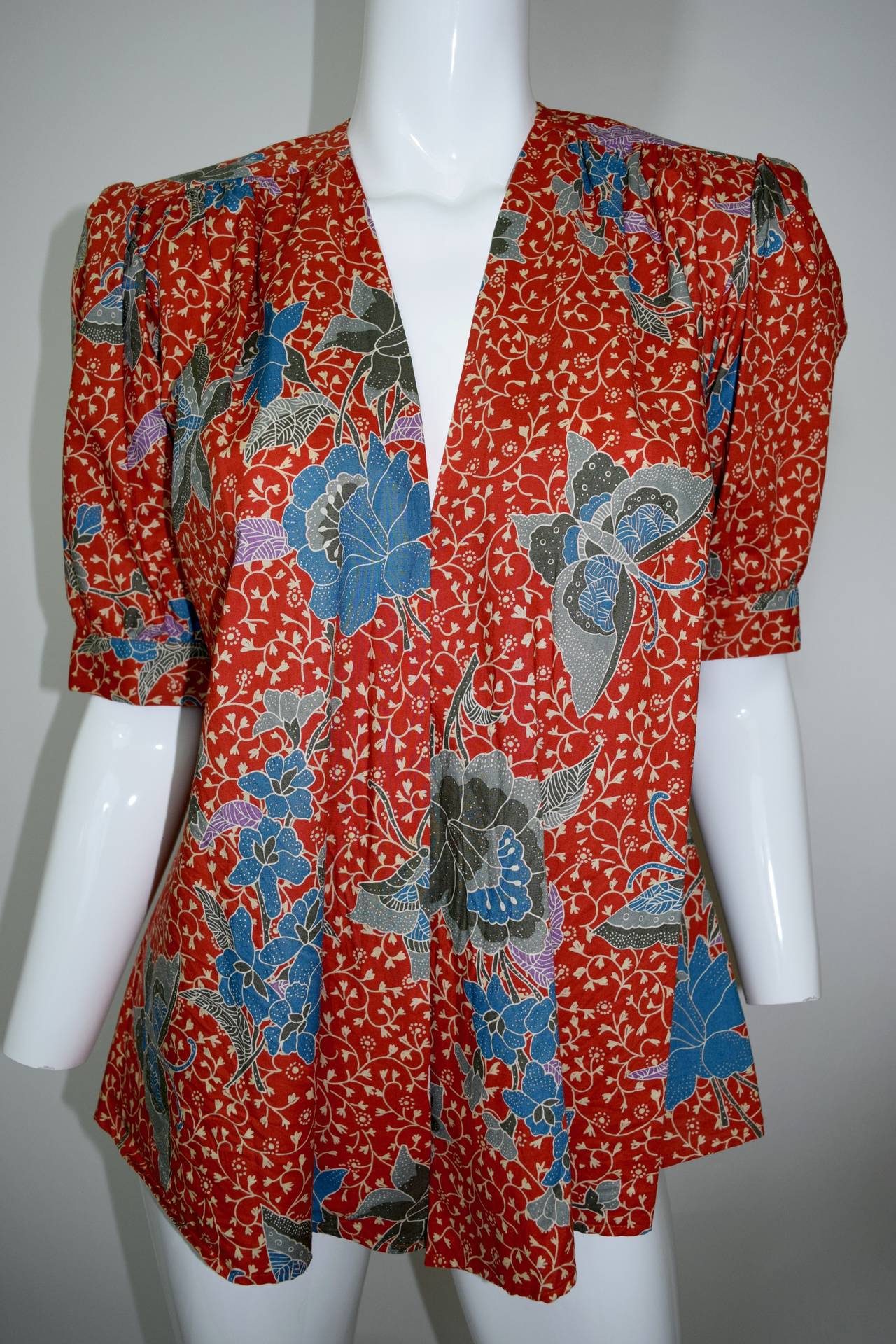 This is a beautiful vintage open front floral and butterfly print cotton jacket and blouse. The green and blue printed butterflies and florals with lavender leaves are on  the YSL opium orange background. Open front and just above the elbow sleeves.