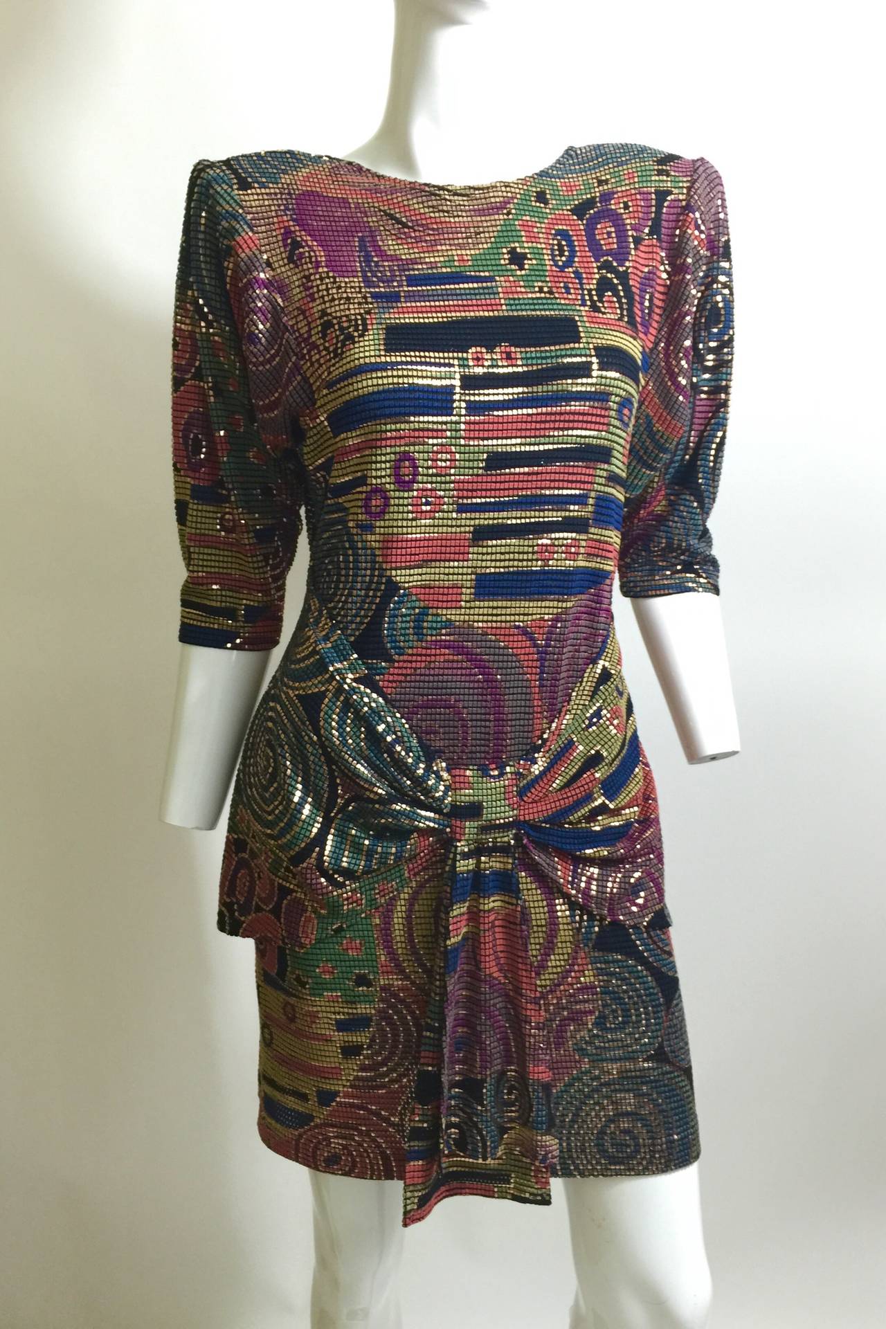 1980s Janine hand painted mosaic mesh dress in shades of purple, mauve, turquoise and green with gold swirls throughout. 
The front of the dress has a round neckline, the shoulders have pads inside (and can easily be removed if you prefer no pads),