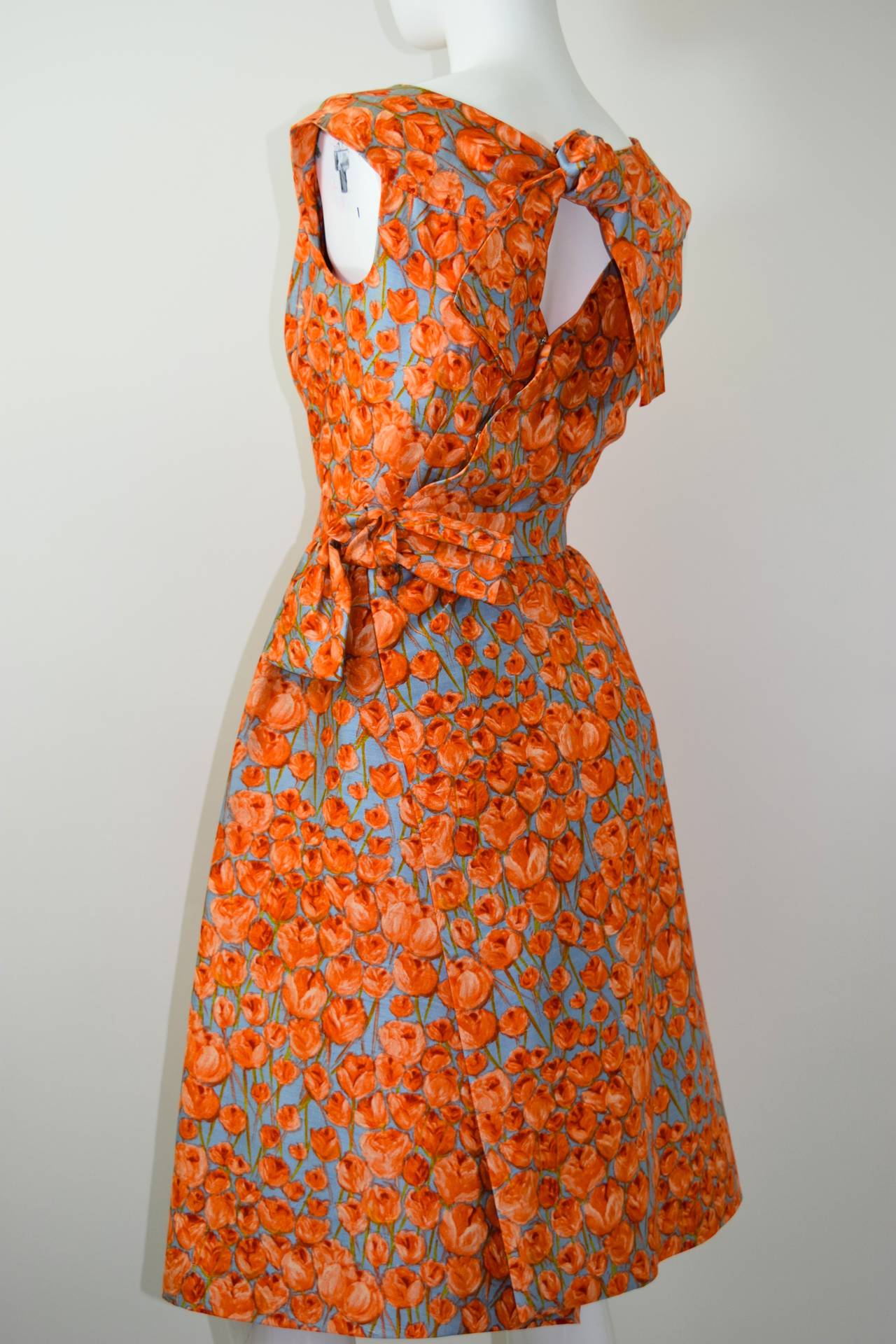 This Hattie is a beauty! The orange floral painterly like print on a robins egg blue background is magical. 
The front of the dress features an inverted pleat at the bust an the skirt potion. two  beautiful bow details ; one at the back of the