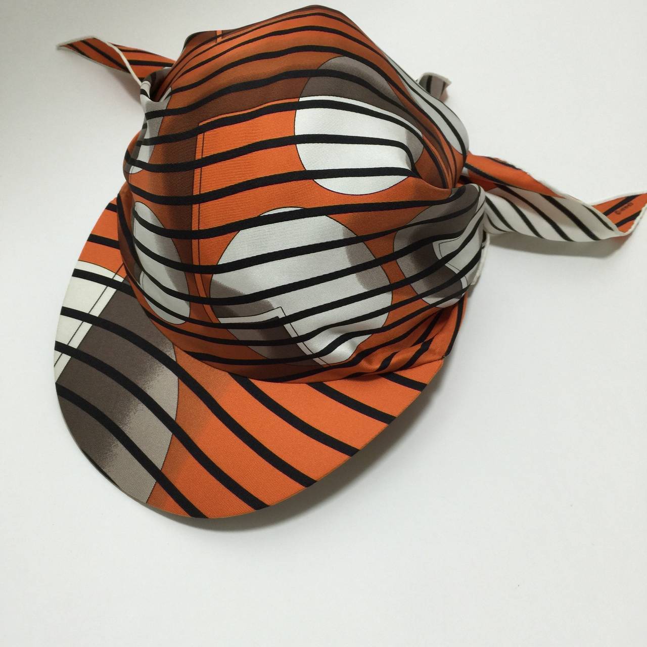 Featuring lightweight orange, black and white geometric print on silk,  a firm cap brim and a soft silk scarf top with self tie back closure. I also love that you can tie the scarf to the front under the chin.

Measurements:
Brim : W- 8.3'' H-