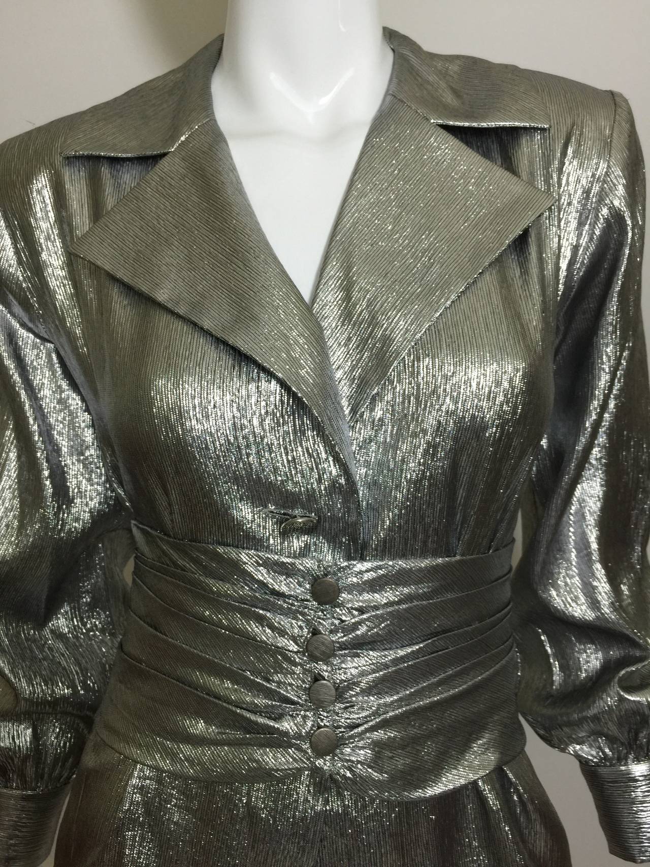 This is a vintage YSL  lightweight  gleaming metallic silver lame' blouse with  a matching wide five button ruched  belt 
The blouse has a relaxed fit with a 3 button front, and a single button cuff.
Lightly padded shoulders (pads can be cut out
