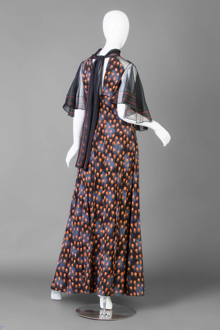 1960's tulip print maxi dress by Jean Varon . The dress has a high rolled collar and illusion bell sleeves with multi color stitch work. There is an illusion panel at the front empire bodice with red stitch work. The maxi length skirt has a graceful