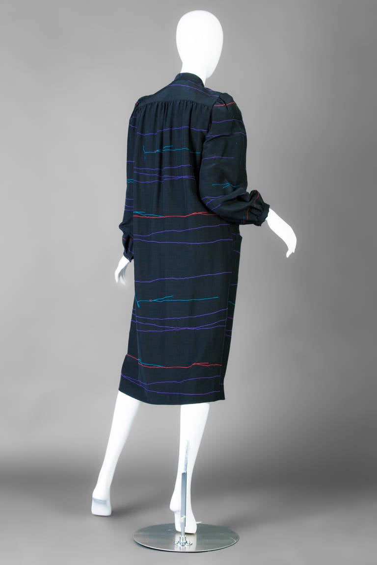 Halston Black Mandarin Collar 1980's button down long sleeve coat dress.
Side fron pockets.
Purple, turquoise, and red squiggle lines.
Buttons up the front with five buttons
Fully lined
shoulder seam to shoulder seam 14 inches