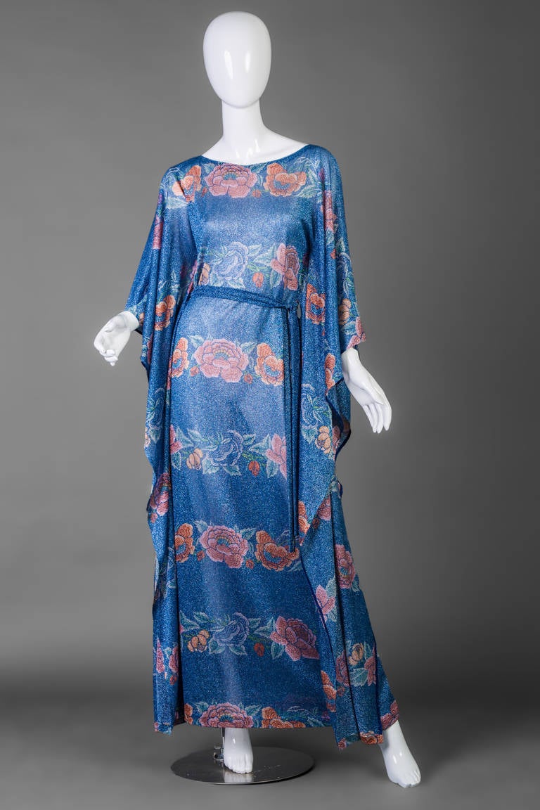 Missoni 1970s caftan dress. Metallic blue lurex  fabric is patterned in florals. .
The dress is unlined and slips over the head. Matching fabric metallic tie belt is included to cinch waist for definition. Fluttery sides.
