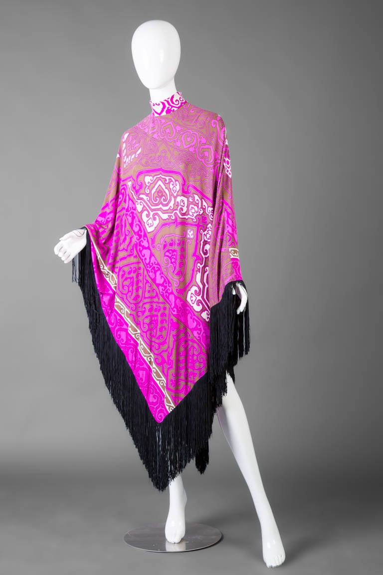 Leonard Paris 1970s silk jersey poncho cape with fringe trim.
Two inch neckline height.
Nineteen inch zip up the back.
Length from center to bottom is fifty four inches, and from sides to bottom is forty inches. Fringe trim is ten inches in