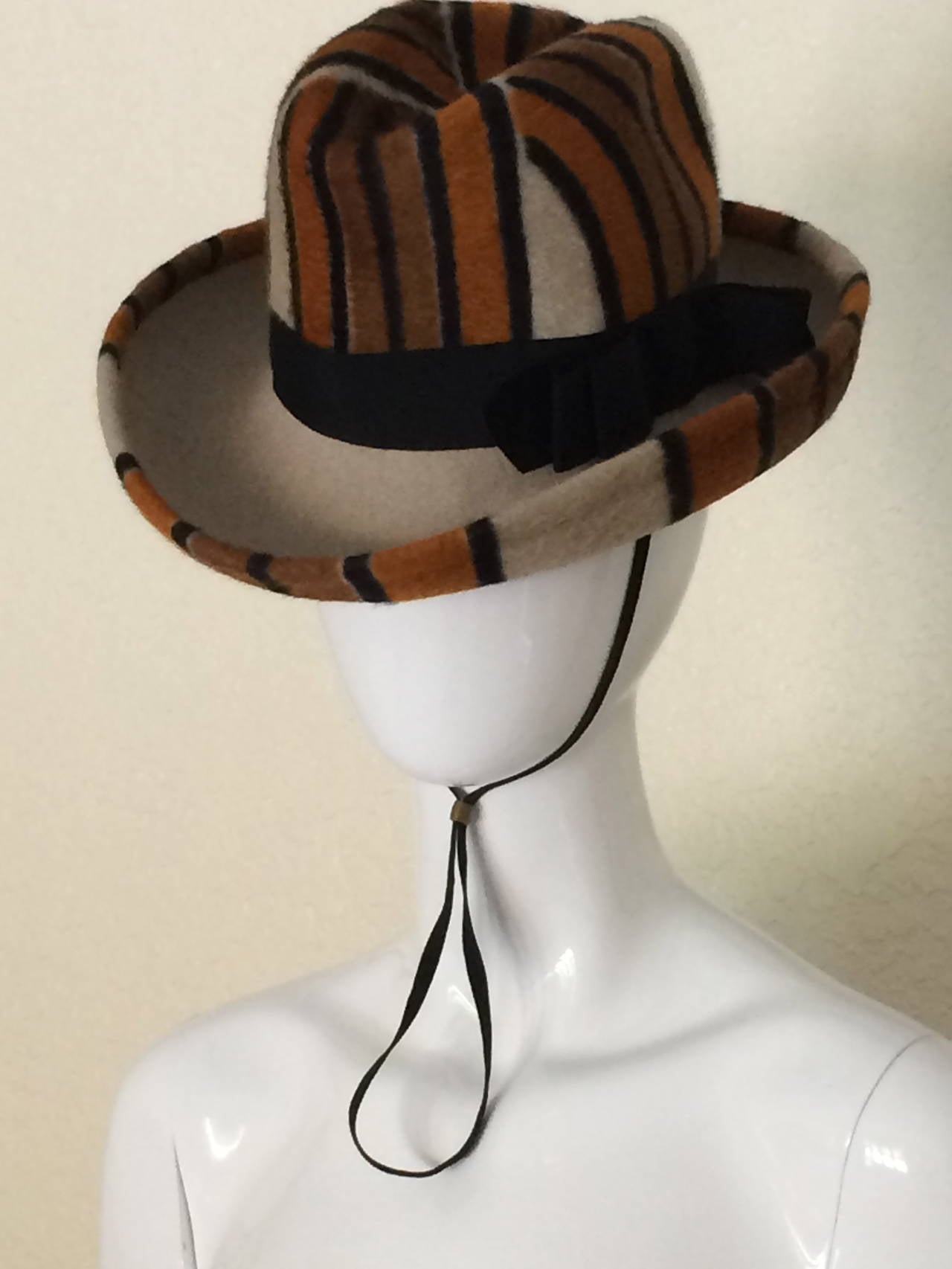 This Vintage Yves Saint Laurent Hat is ultra cool. Featuring a mod stripe pattern in orange, brown and black adjustable chin strap. This hat appears to be unworn in excellent condition. Best detail is: check out the underside of the brim, it is