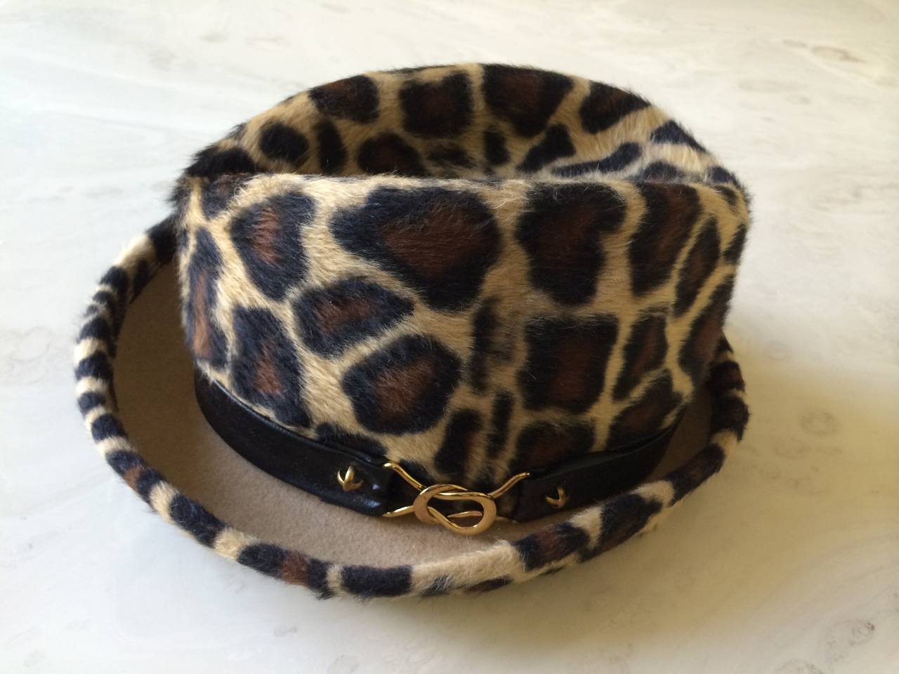 Vintage Yves Saint Laurent Leopard Print Hat.
Black leather  band with gold hardware trims this leopard print felt hat.
Approximate measurements. Front to back inside hat 7 1/2 inches
Inner circumference. 21/ 22 inches. Excellent Condition.
