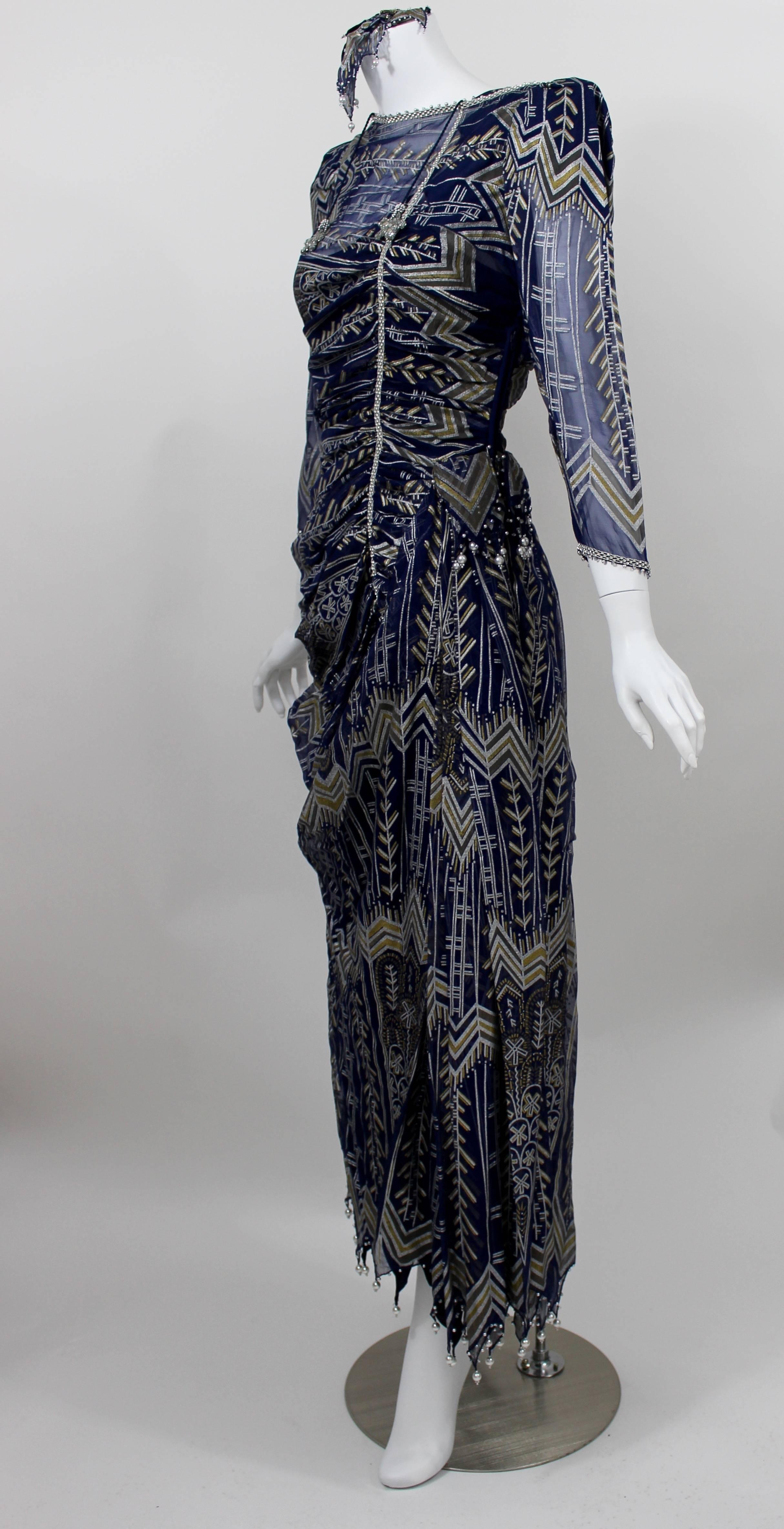 This Dress from Zandra Rhodes is fashioned from a hand painted navy blue  sheer silk chiffon.

Rhinestone and hand sewn pearl accents detail the dress.

Draping around the middle of the dress is figure flattering, and slimming.

A matching midnight