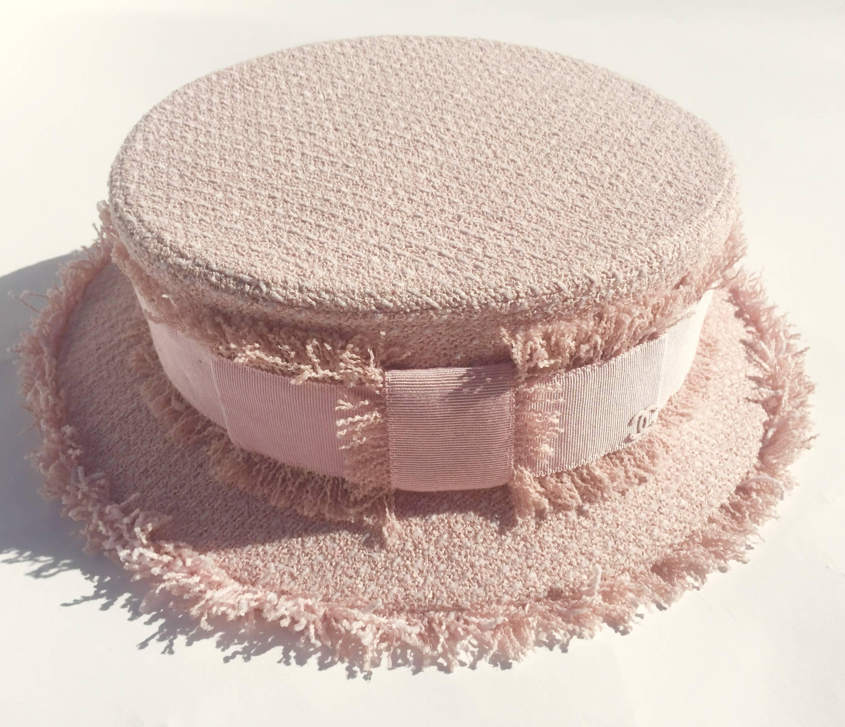 A chic Chanel hat in baby pink tweed From the Fall 2009 collection. This hat is pink perfection, made  from classic Chanel tweed with frayed trim around the brim  and on both sides of the pastel pink grosgrain ribbon. The ribbon trim is finished
