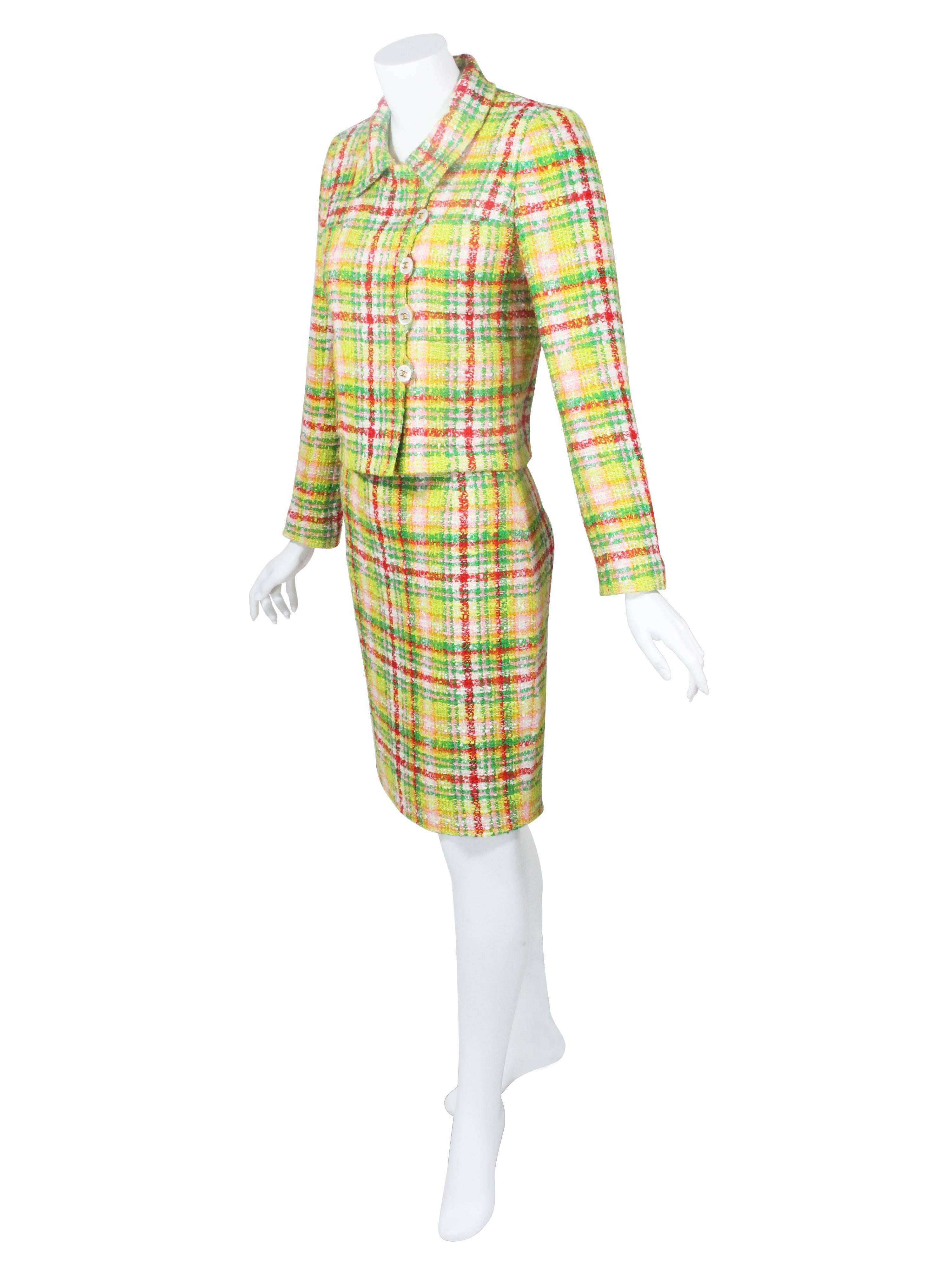 An forever classic skirt suit from the house of Chanel .Done in a green and multicolor bouclé plaid. Jacket features padded shoulders, four patch pockets and 5 beautiful pearlized with gold CC button closures at front, and four buttons on each