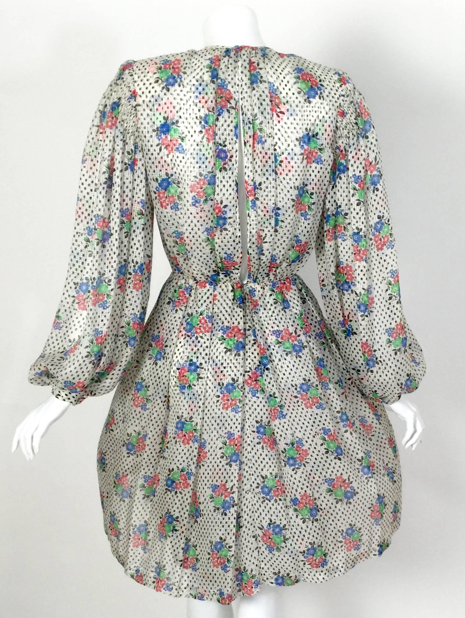 This is a stunning creation from James Galanos circa 1970. 
Done in an airy silk chiffon with a pattern of black dots, and playful florals in red, green and blue. 
From the round  neckline, to the delicate gathers just below the shoulders and