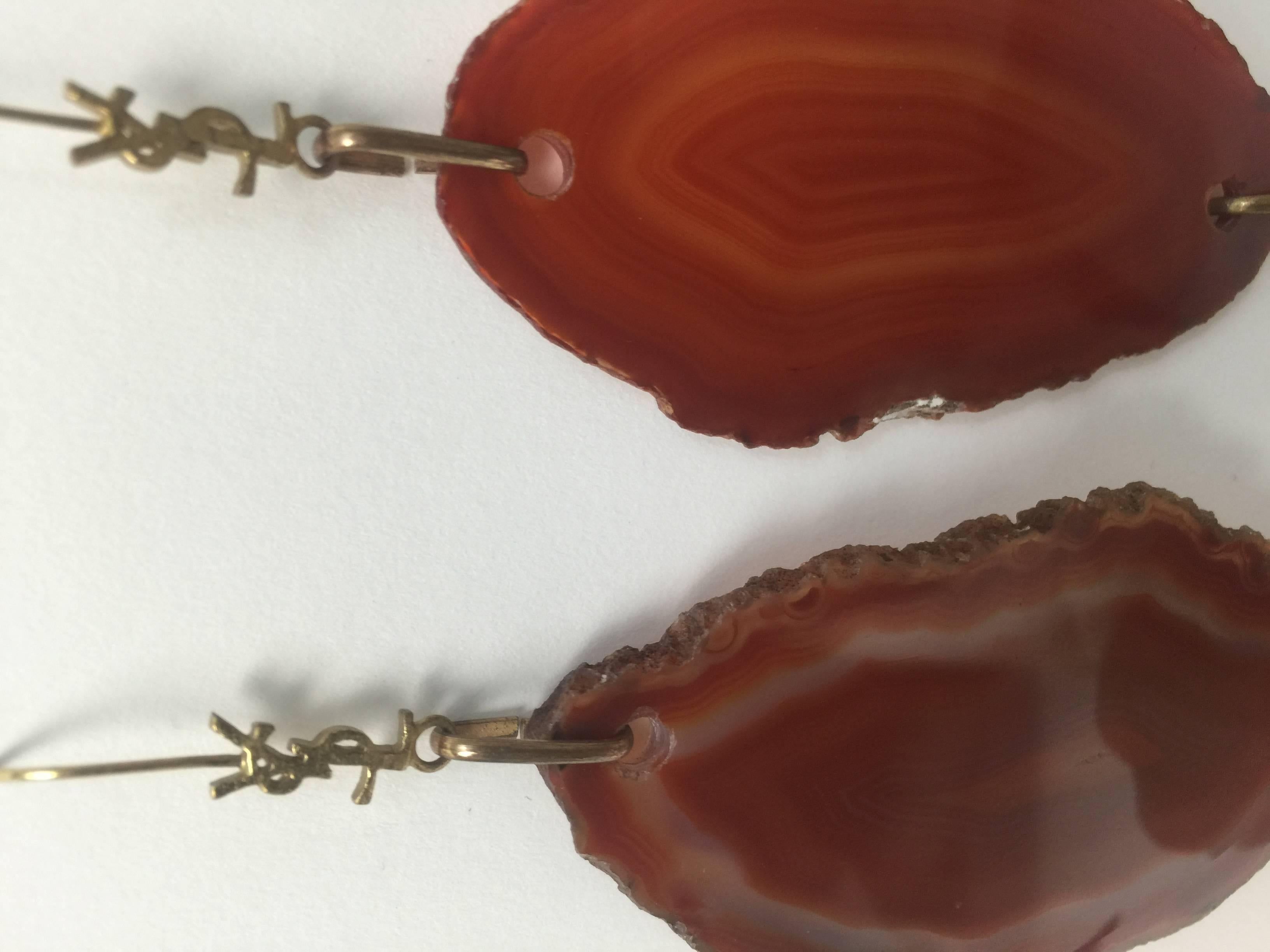 These fabulous Yves Saint Laurent earrings are from the Arty collection. A polished drop of sliced richly hued agate hangs from a polished gold -tone YSL signature setting .  A  textured bead dangles at the bottom. Fisherman hook back.
Excellent