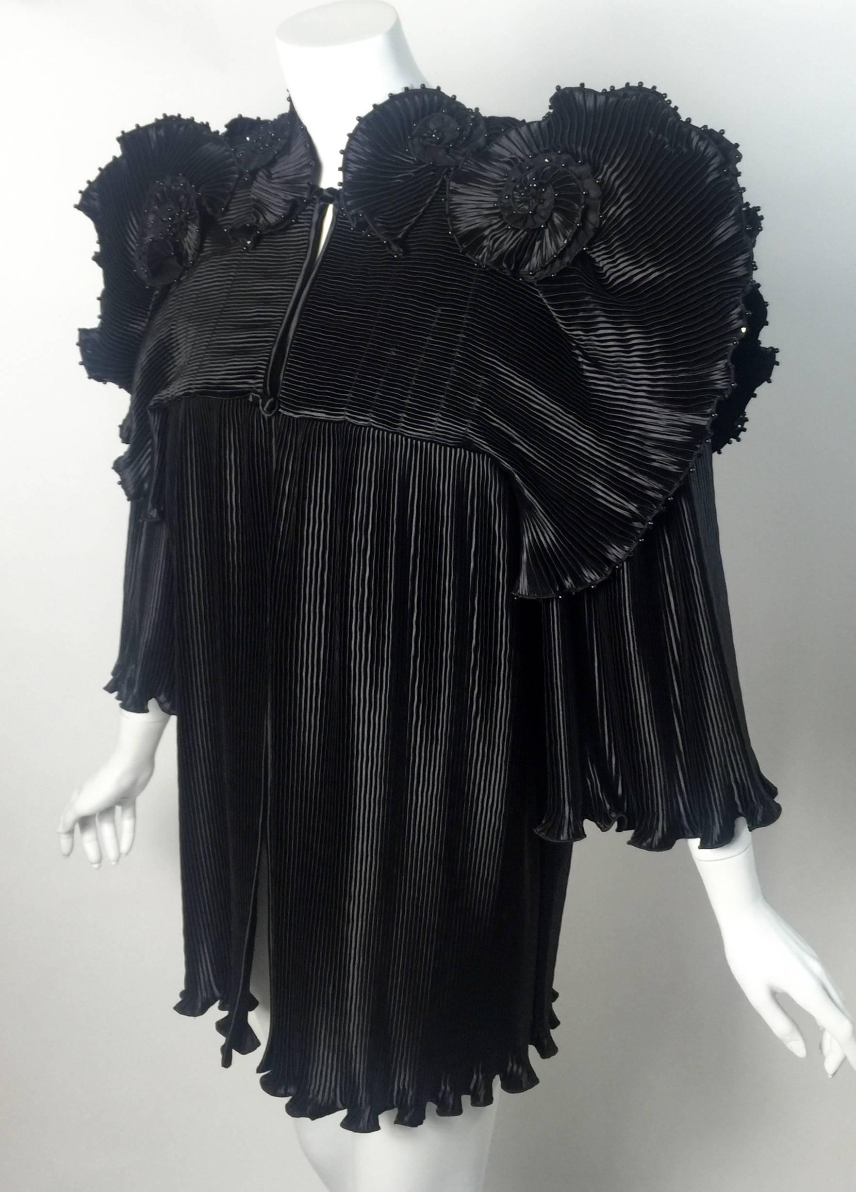 An iconic 1970s Zandra Rhodes jacket. This spectacular jacket done in all black with micro accordion pleats throughout. Beautiful fabric sculpted flowers along the top near the shoulders and  dramatic fanned ruffles along the shoulder line. finished