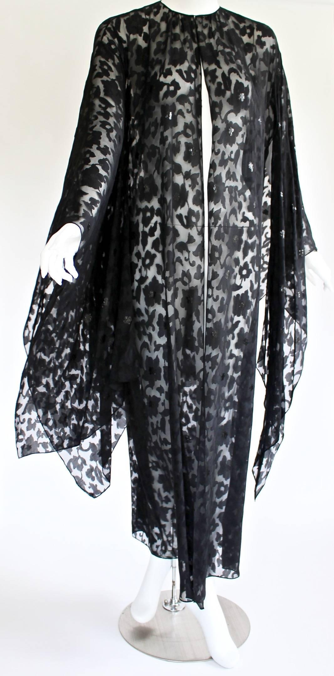 This Nina Ricci kimono is an effortless way to layer on luxury. The diaphanous beauty is designed from light-as-air black silk featuring a devoré print of gorgeous swirling flowers, vines and leaves. Many of the flowers are dressed up with black