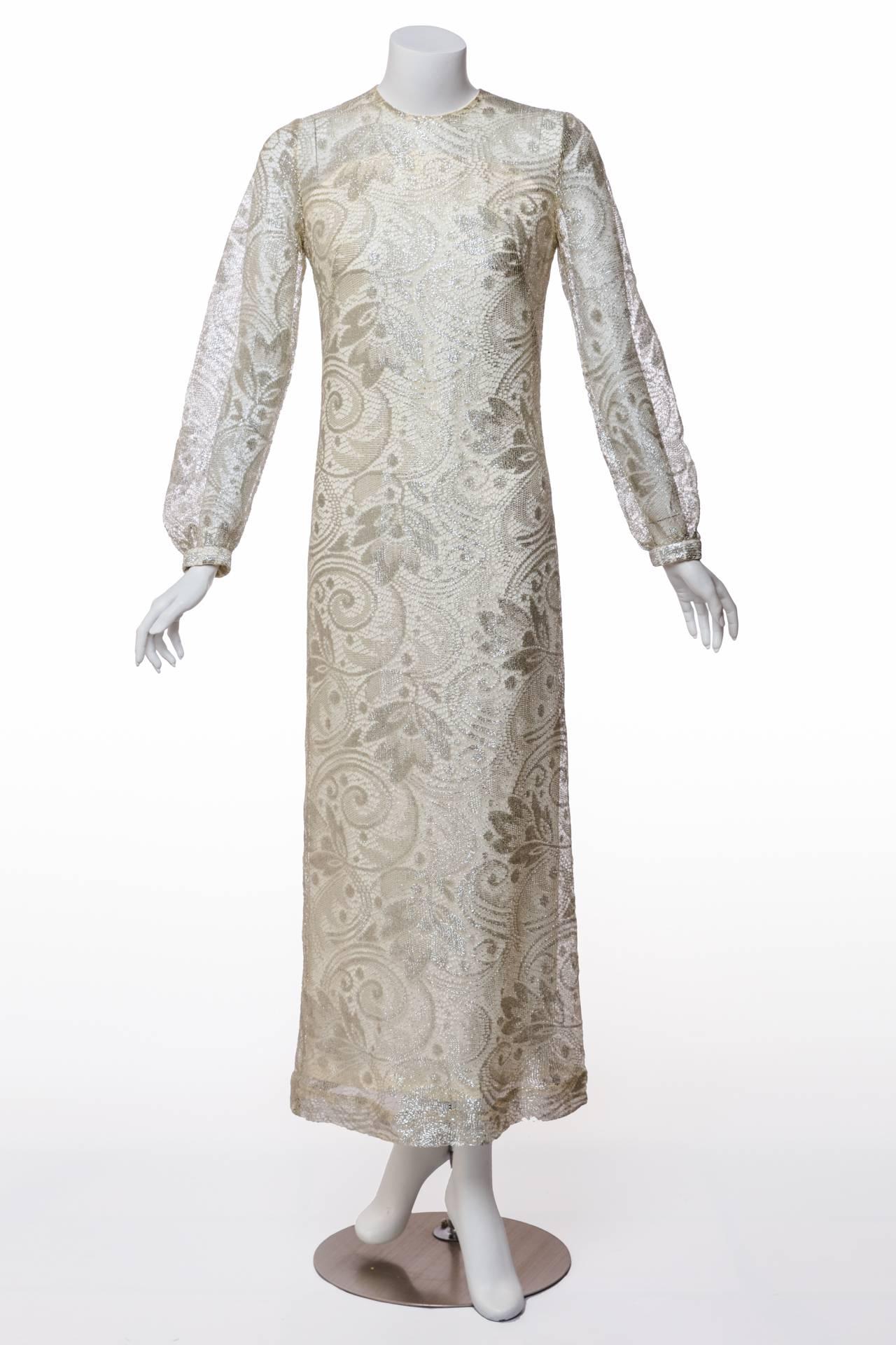 A spectacular silver paisley lace makes this Sixties gown an exquisite treasure from the past. Lustrous and full of gorgeous swirls and flora, it is cut in a column silhouette to best display its beauty.  An ivory crepe lining further enhances the
