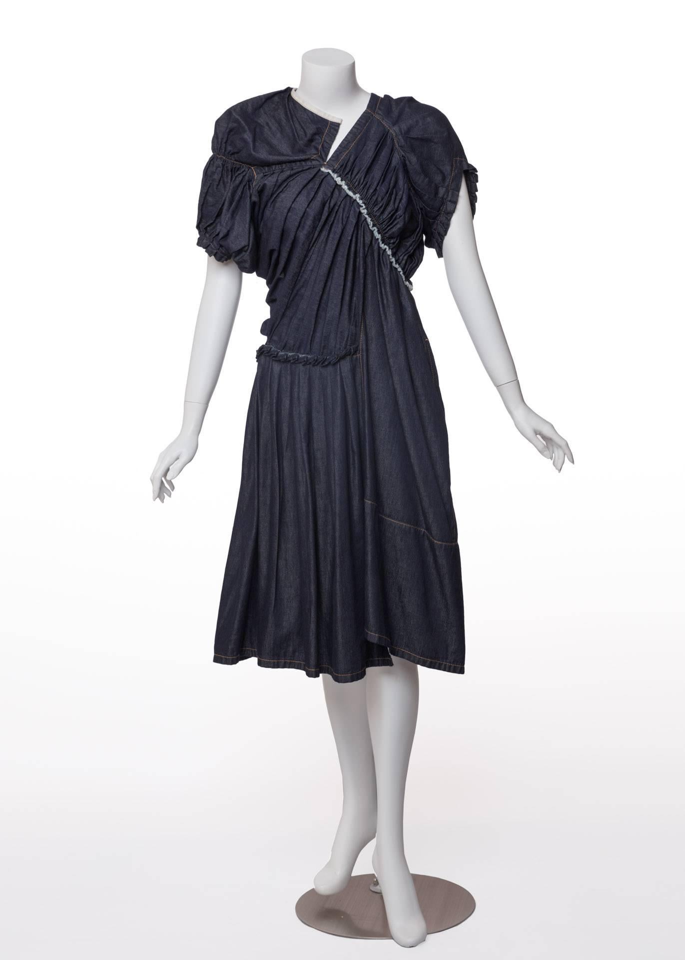 Denim is masterfully rethought in this avant-garde Tricot Comme des Garçons day dress . The utilitarian textile in a rich indigo blue is gathered, pleated and ruffled to take on a lightweight appearance in the pretty knee-length silhouette. The