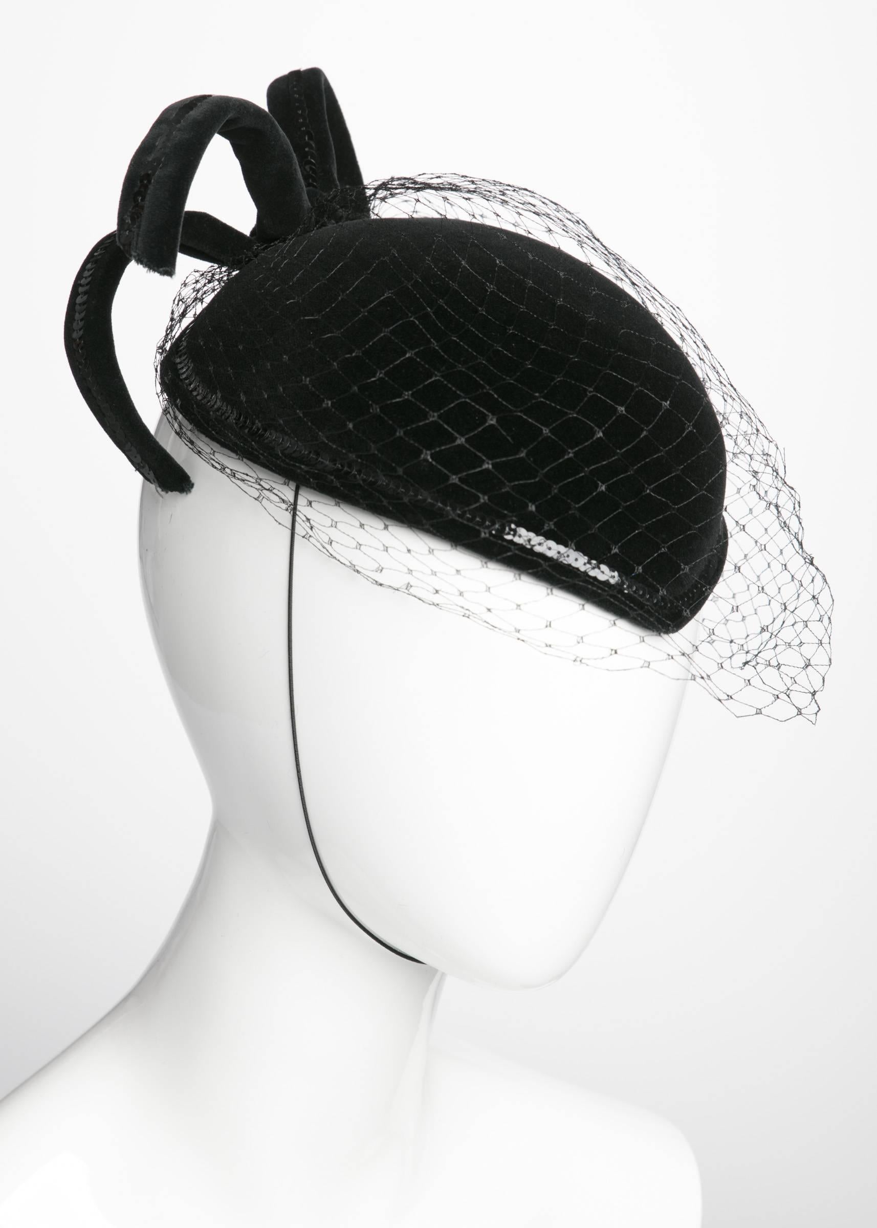 Forget little black dress, this little black hat will make you feel royal. Made by Philip Somerville, a London-based milliner who made innumerable hats for Queen Elizabeth, this black velveteen widows peak hat elegantly dips down over the forehead.