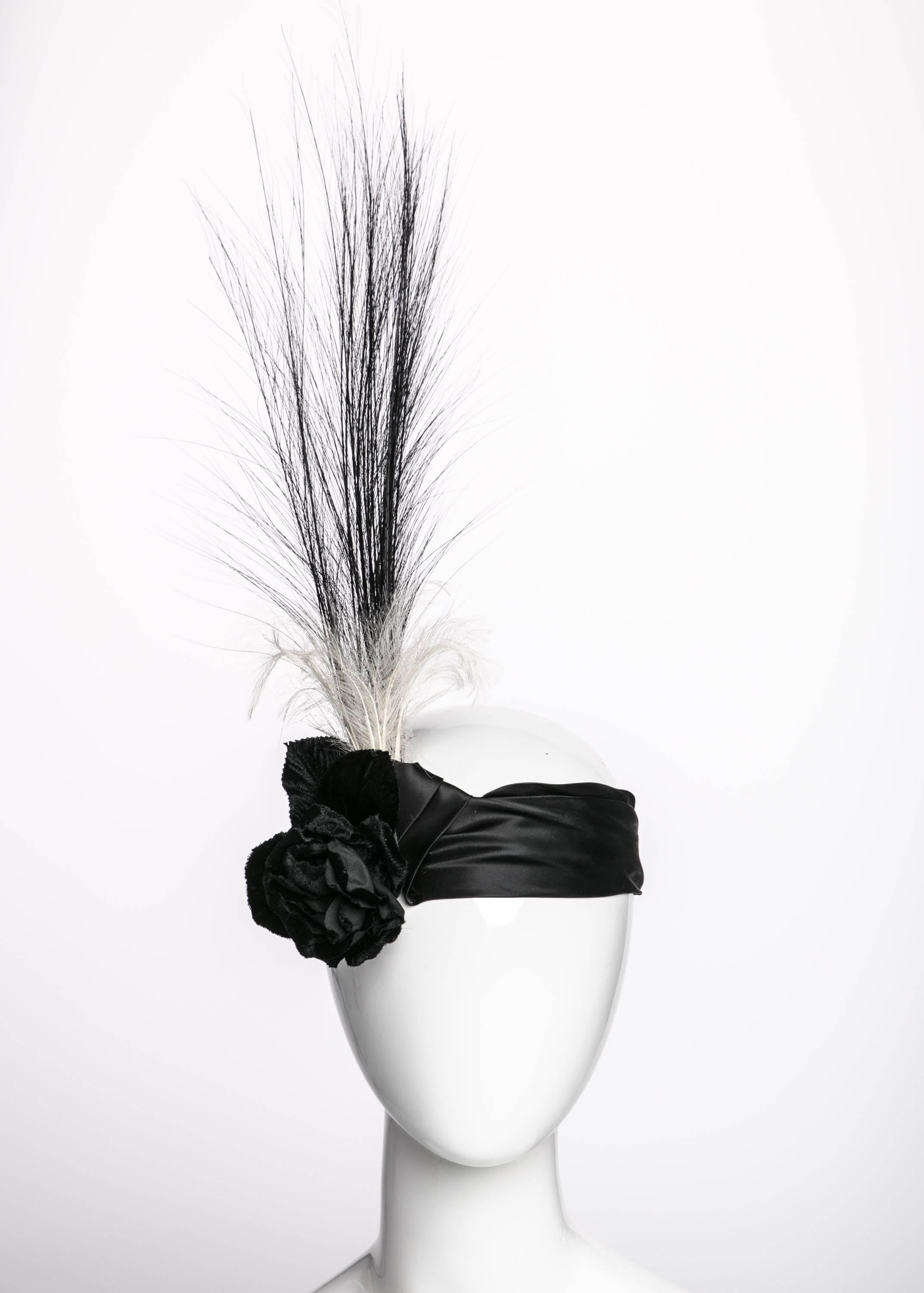 Like a George Barbier fashion illustration come to life, this early 20th century inspired band wraps the head softly with a folded black satin sash. A fixed satin knot combines gracefully with a black velvet rose on the right side. Tall black plumes