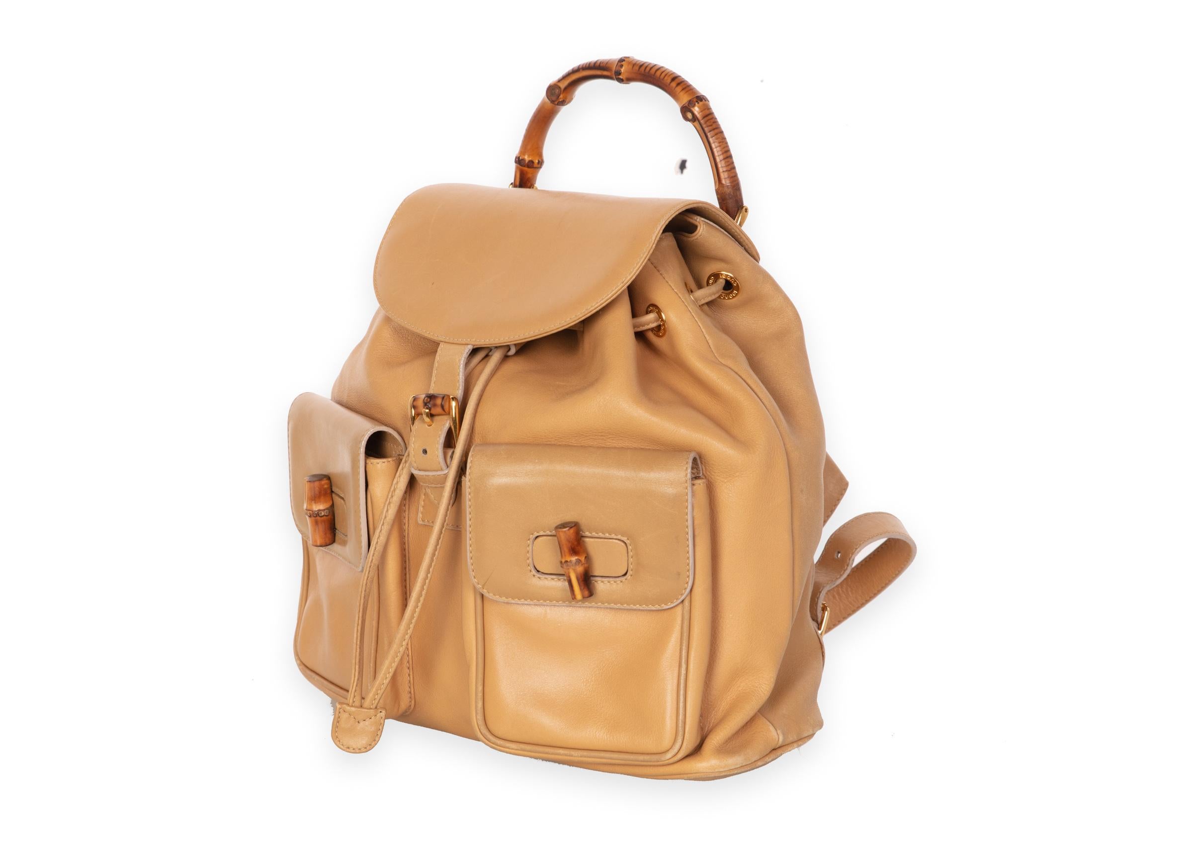 Tan leather vintage Gucci bamboo backpack with antique gold-tone hardware, tonal leather trim, dual flat shoulder straps, bamboo rolled top handle, dual gusset pockets at front, tonal jacquard woven lining, single zip pocket at interior wall,