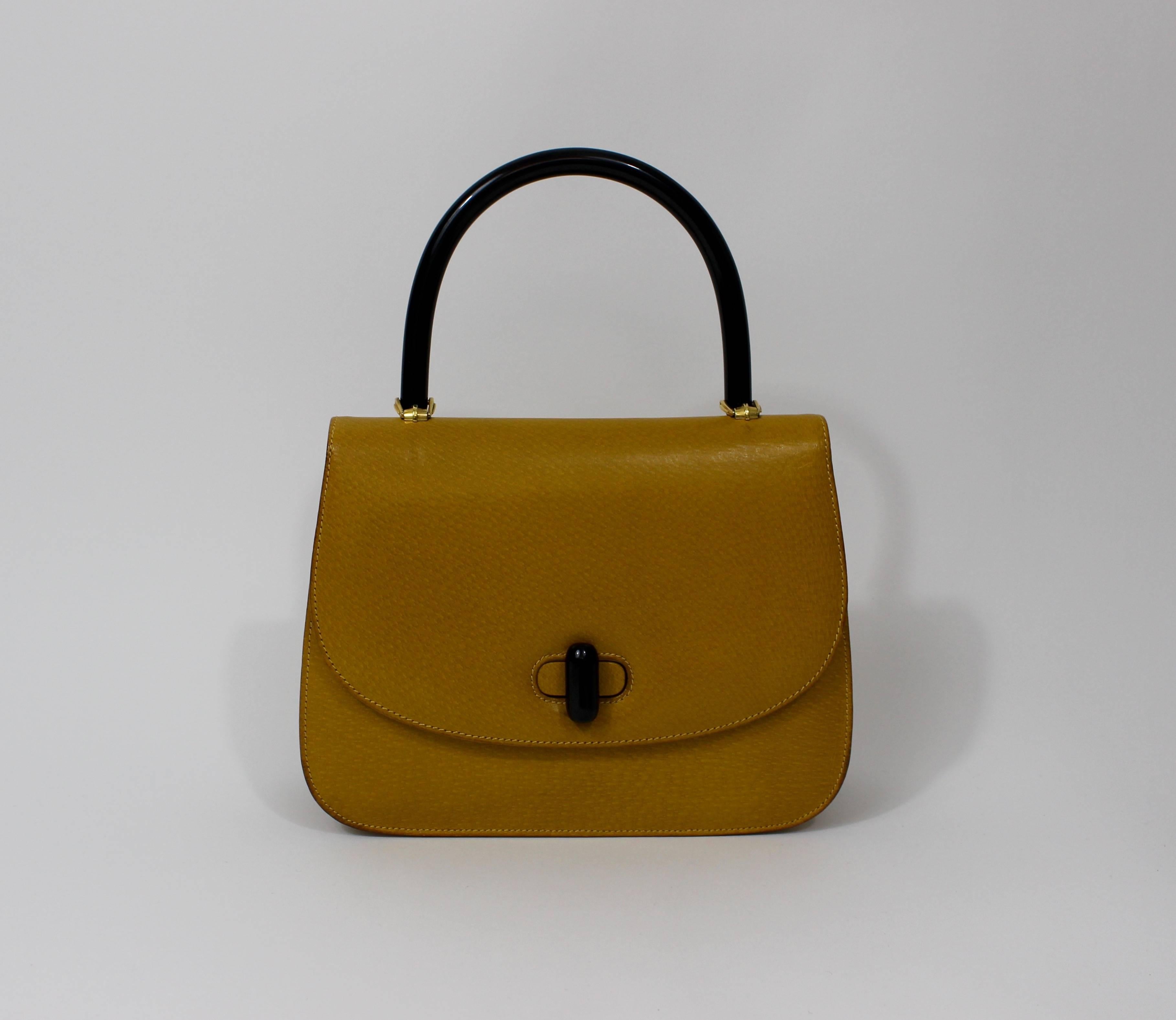 A 1960s Gucci purse in  mustard yellow leather with black bakelite  top handle and clasp. 
Gold tone metal hardware. 
Golden 