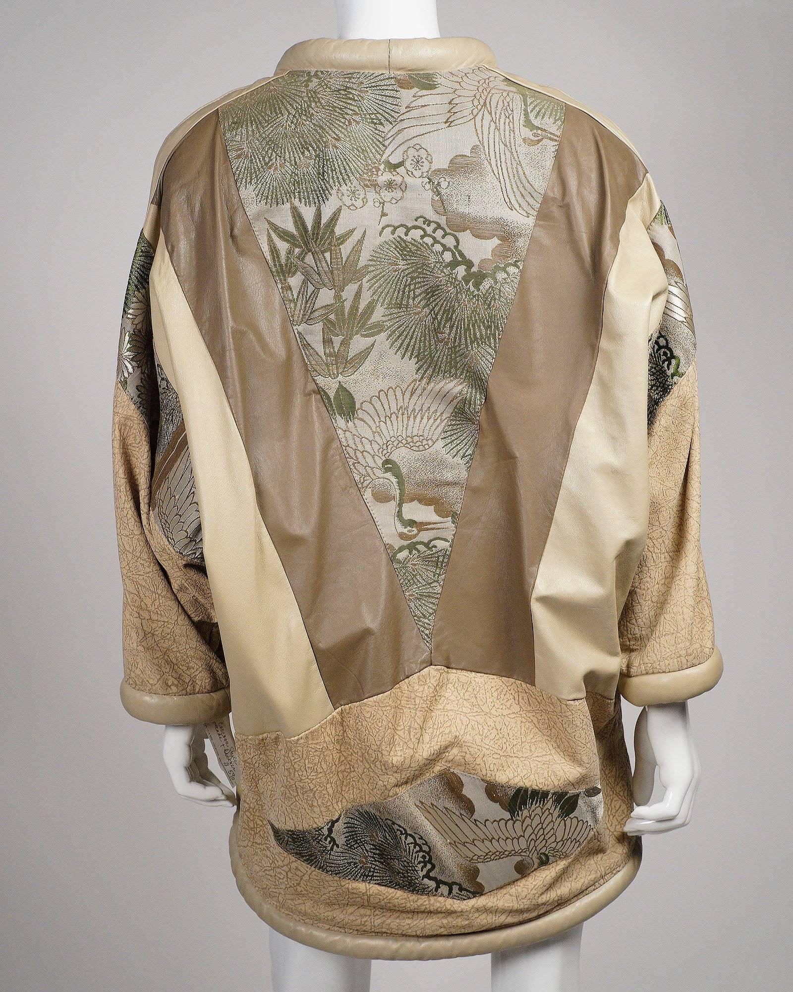 Opulent Japanese Style cocoon coat in leather with a silk brocade lining. Hand embroidered crane and bamboo leafs strips adorn the front with a single closure clasp. 