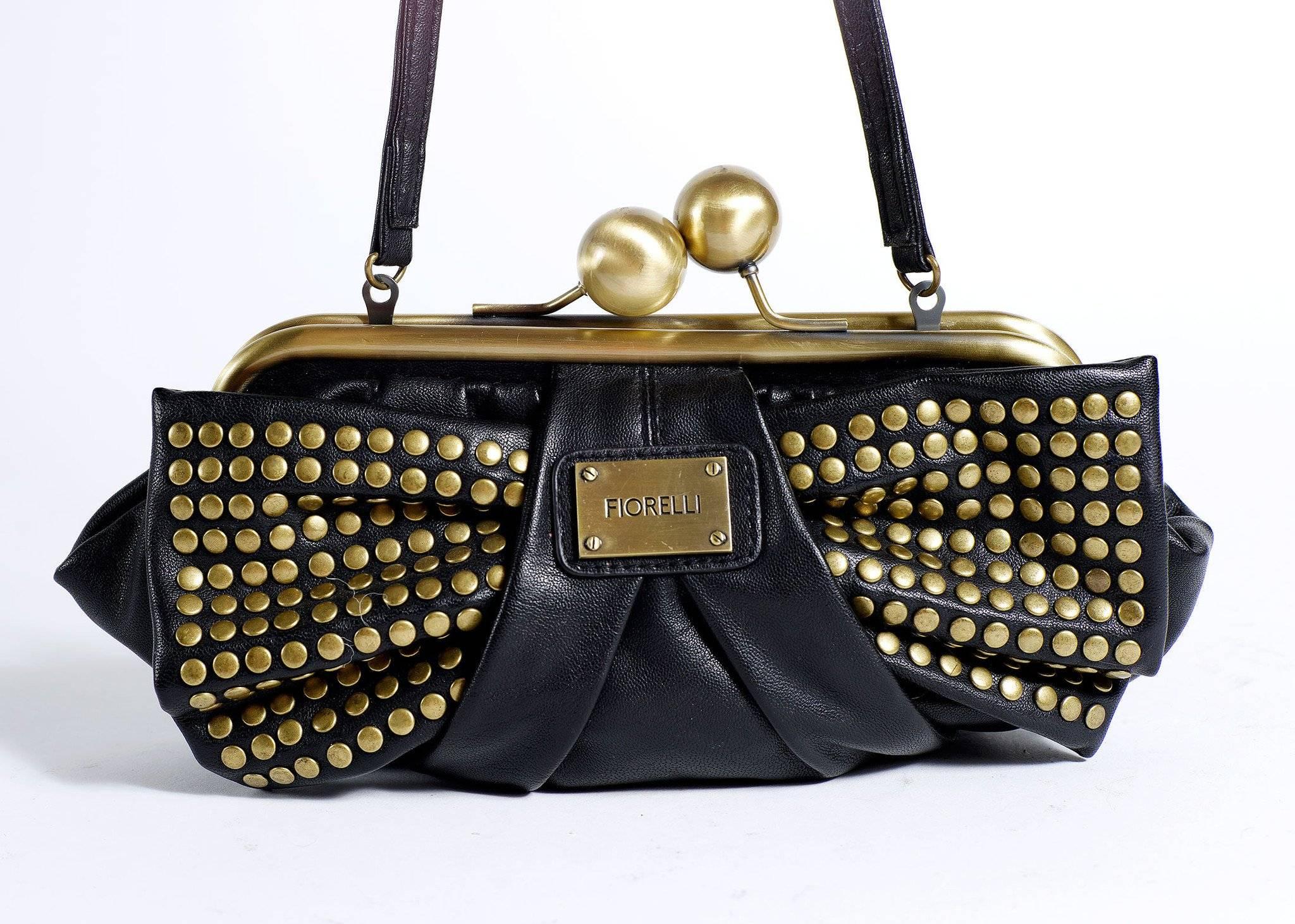 Fiorelli black leather Handbag with brass studed bow. There is a brass frame closure and Fiorelli medallion along the front.

Messurments
9 inch strap
6 1/2 inches long
12 inches wide

Good Vintage Condition: Please remember all clothes are