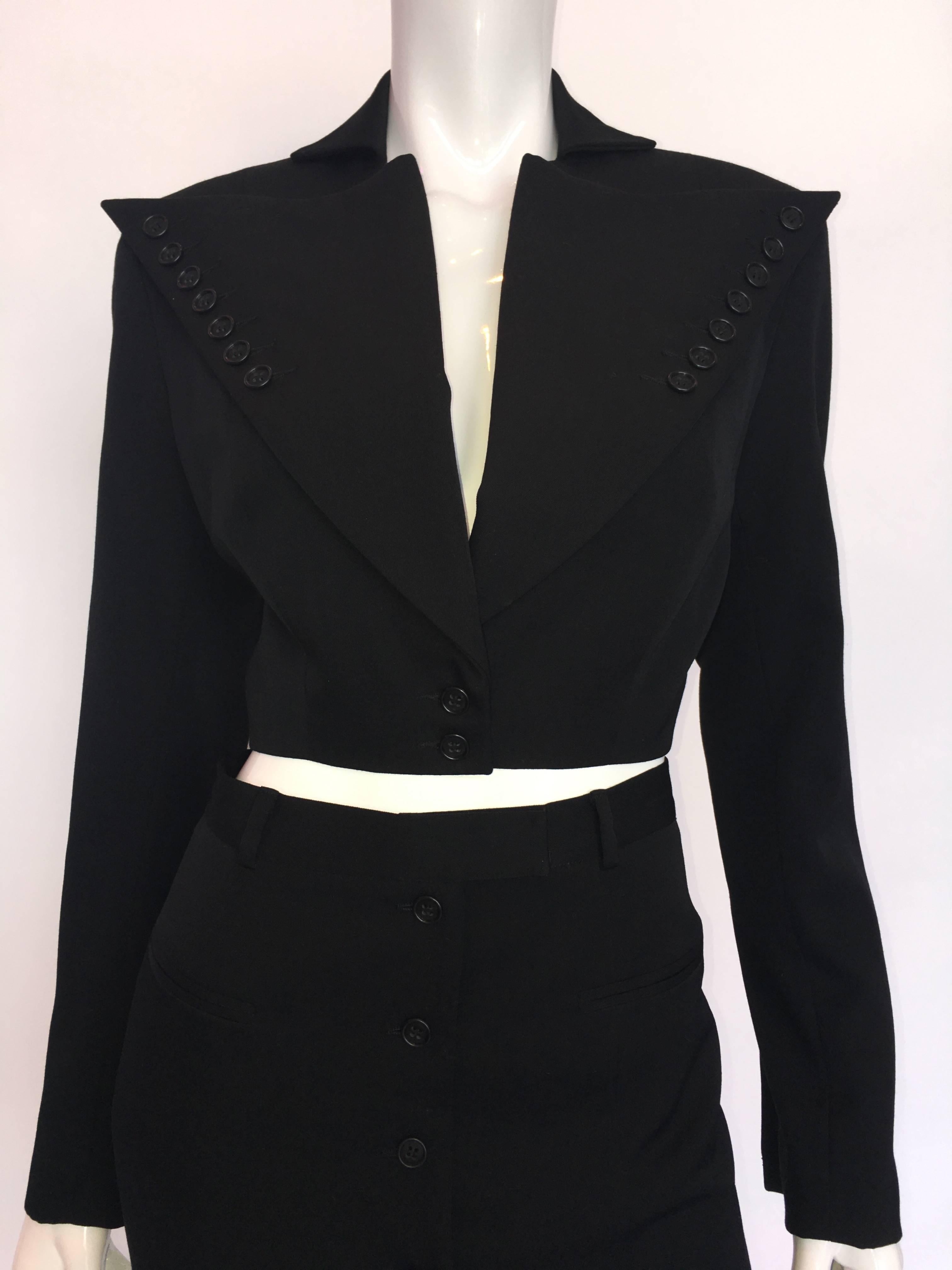 combinaison à mini-jupe en laine noire OMO by Norma Kamali des années 1980 avec détail des boutons

Fabriqué aux États-Unis
Etiquette de taille : 6

Mesures (prises à plat) :
Veste :
Epaules - de la couture à la couture : 17