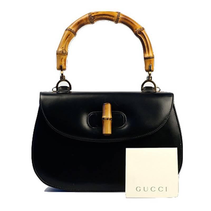 Black leather Gucci handbag with bamboo handle and twist closure. The handbag comes with a red lining and original serial number.

Color: Black 

Good Vintage Condition:Please remember all clothes are previously owned and gently worn. There is a