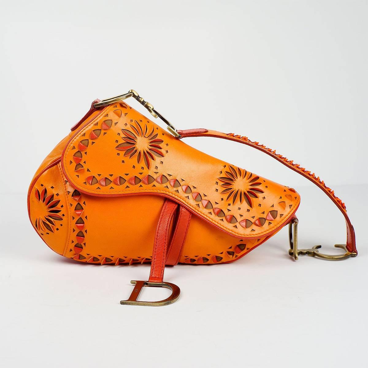 Christian Dior limited edition orange and red saddle shoulder bag with cut out detail and large hanging Doir initials. 

Authenticity tag # 44884372385942, Made In Italy. 

Measurements: 9 inches across the top, 12 inches diagonal 

Good Vintage