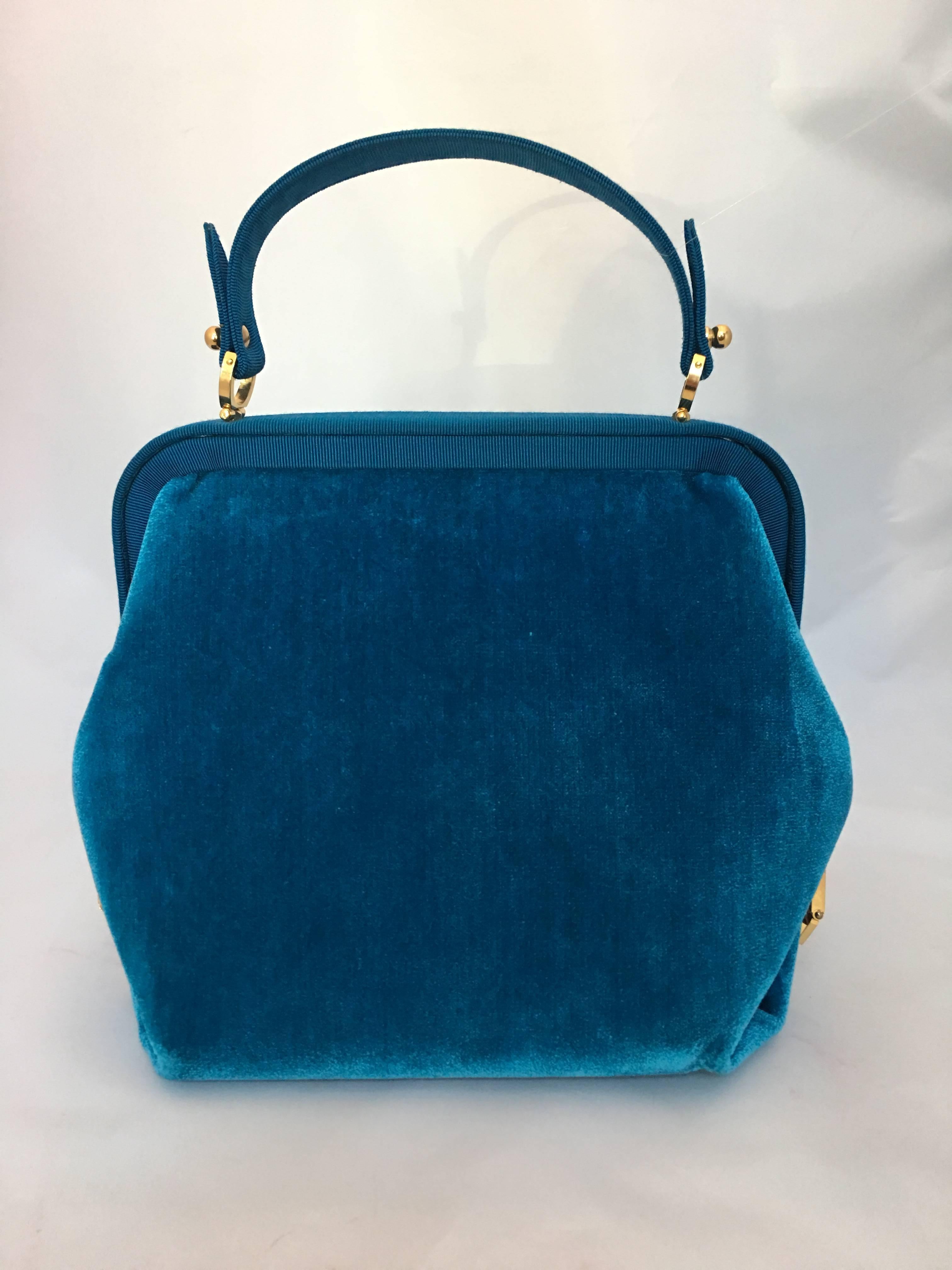 Roberta di Camerino Turquoise Teal Blue Velvet handbag with cut velvet ribbon design across middle front of bag. Grosgrain ribbon frame and handle with gold hardware closure and side gold locks. Inside has one zip pocket and one slit pocket.
Bag is