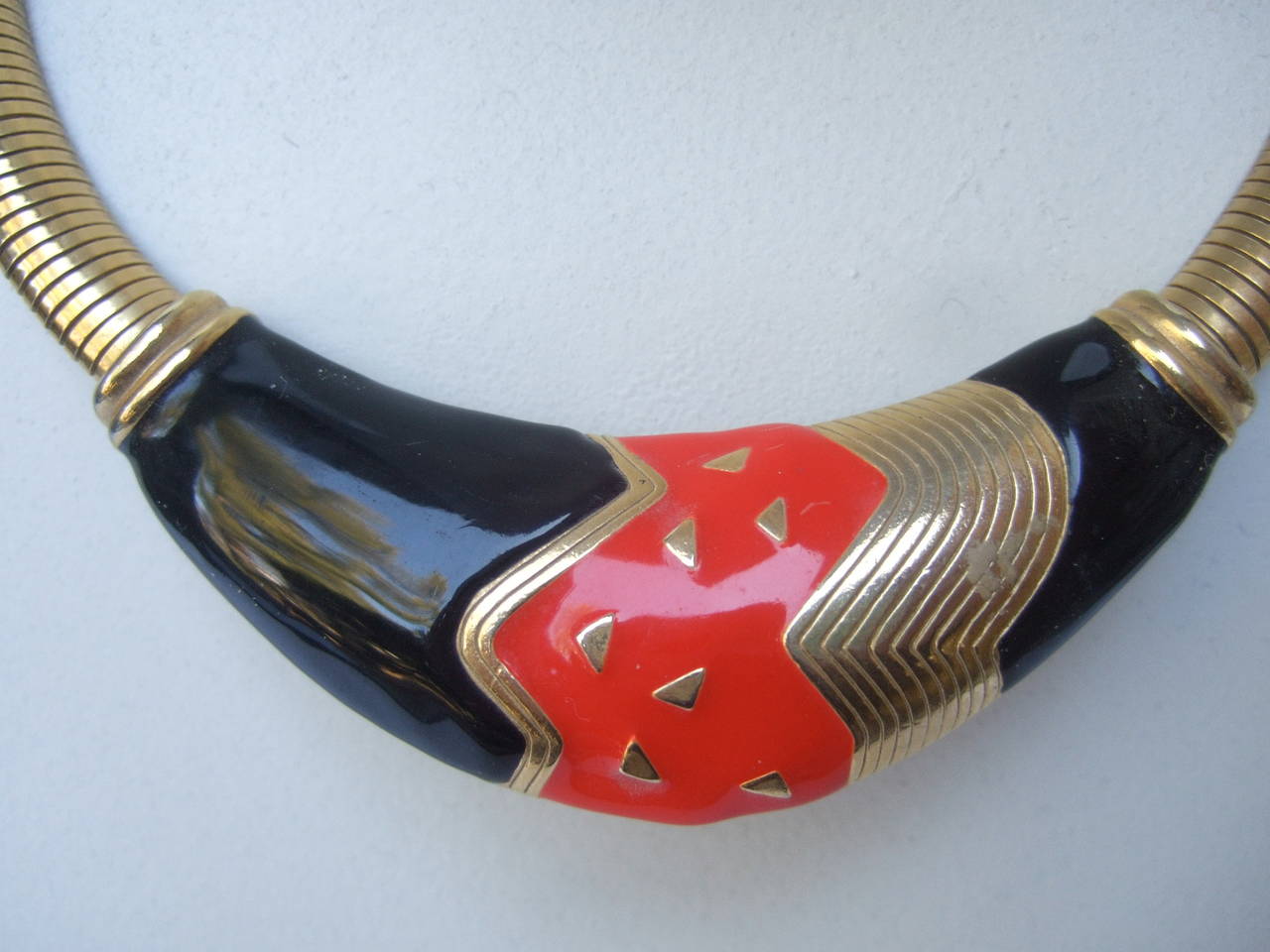 Sleek black & red enamel gilt metal choker style necklace c 1980
The stylish necklace is designed with a bold abstract center plaque
The red & black enamel is juxtaposed with gilt metal accents

The necklace transitions into wide gilt metal