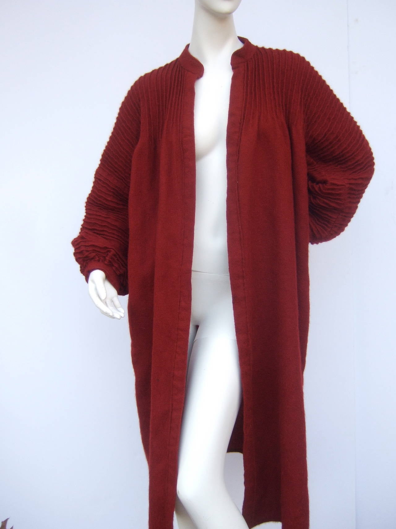 Geoffrey Beene Burgundy wool cocoon coat for Saks Fifth Avenue
The stylish light weight wool coat is designed with unique pleating detail that frames the neckline & runs down the voluminous sleeves

The coat is designed with two hip seam pockets.