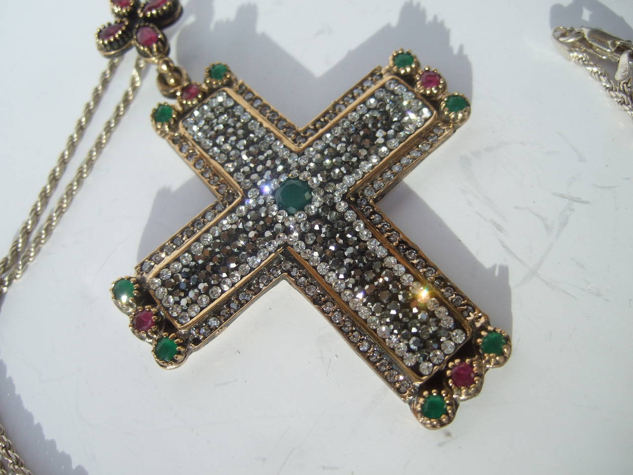 Sterling large crystal & semiprecious jeweled cross pendant necklace
The ornate jeweled cross is encrusted with glittering crystals. The center & borders of the cross are embellished with deep pink & emerald green color semi precious man made